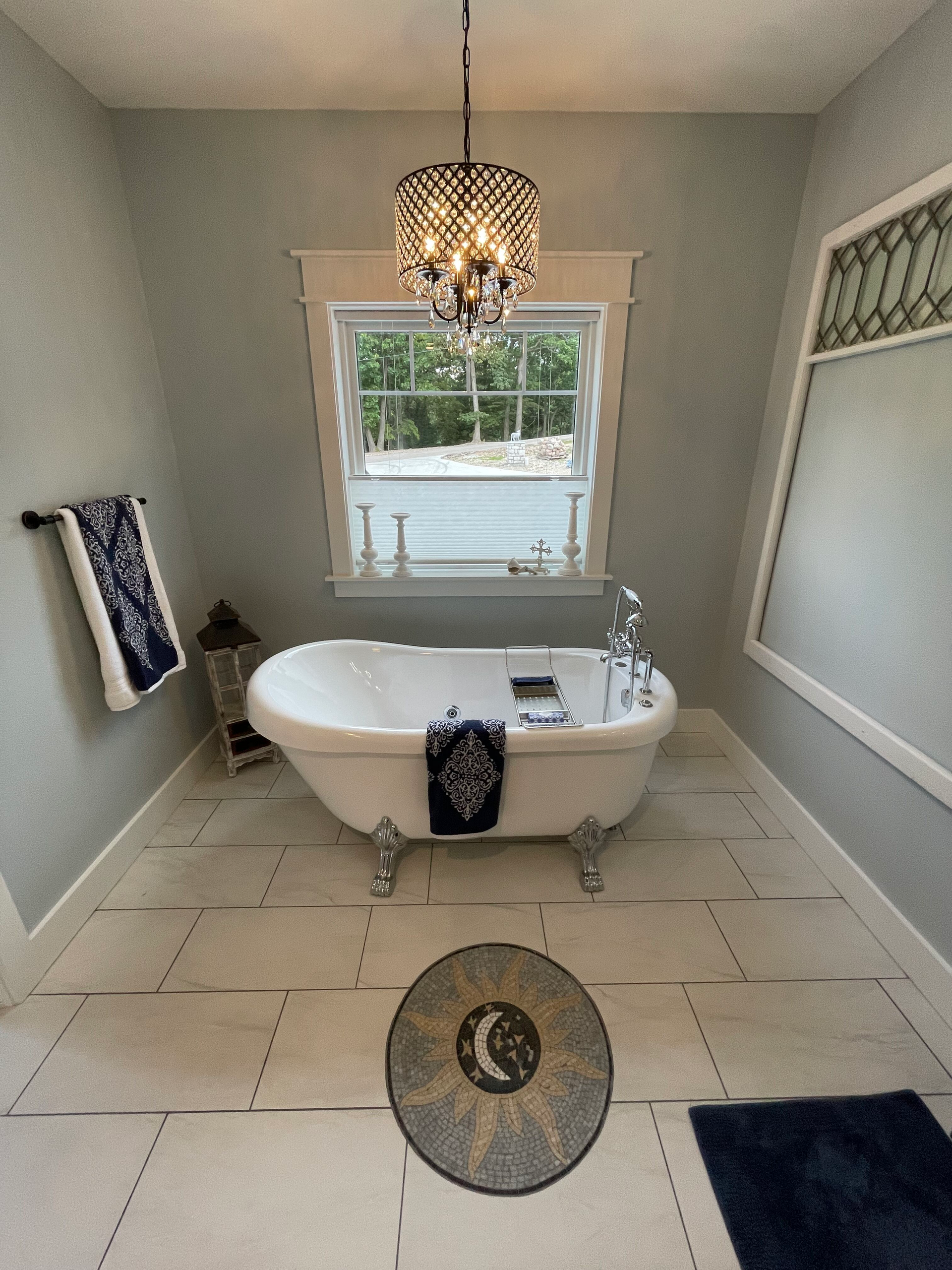 A bathtub in a bathroom with a chandelier hanging from the ceiling