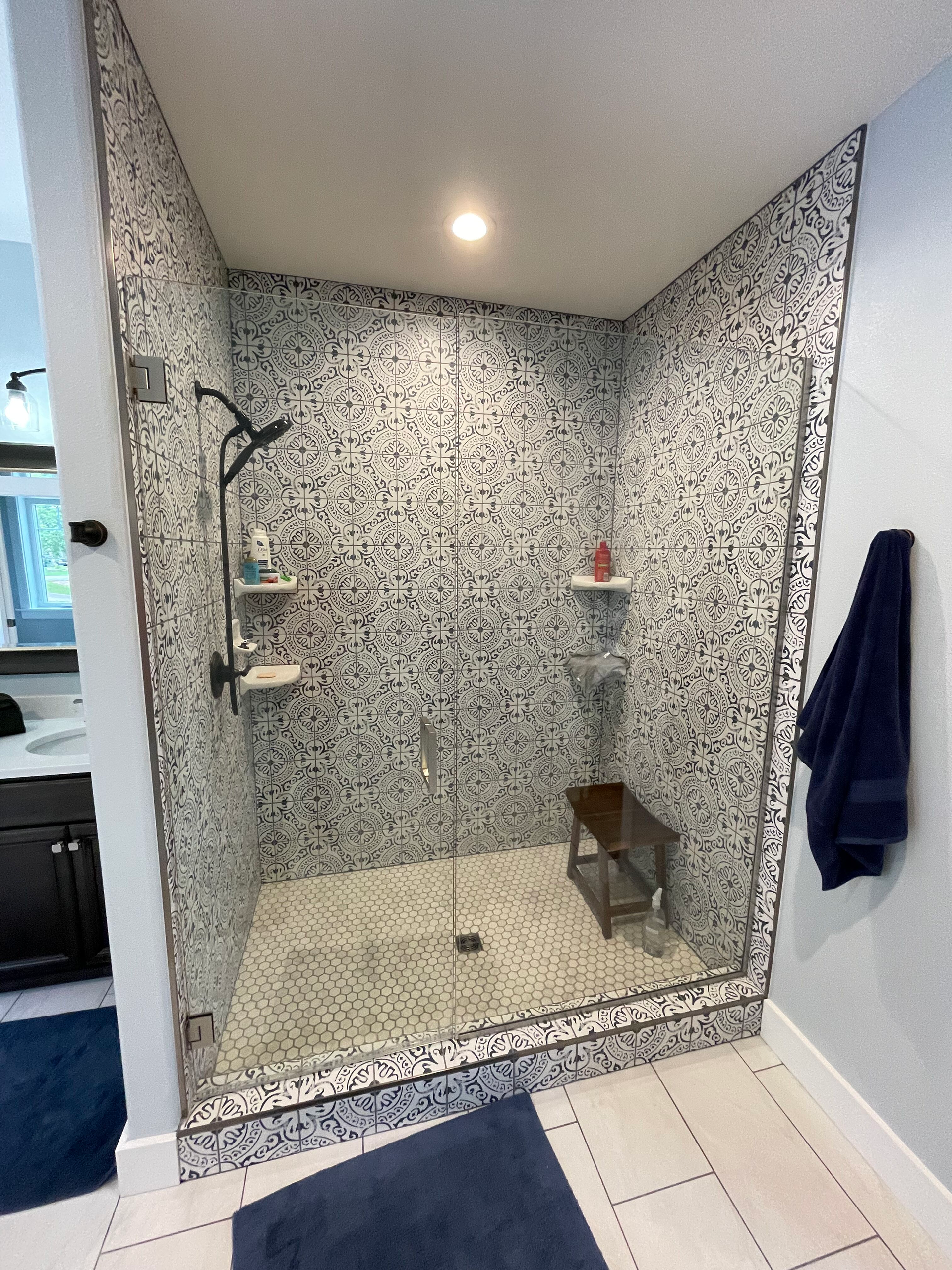 A bathroom with a walk in shower with a glass door