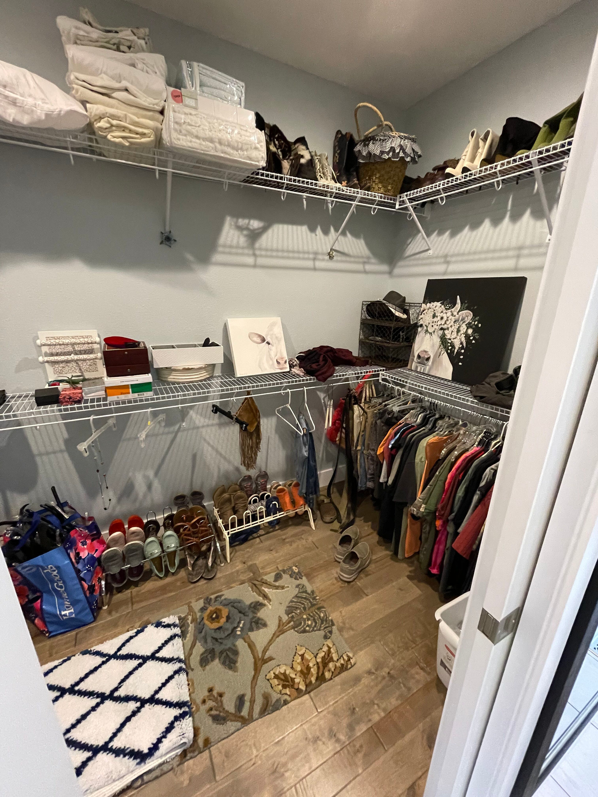A walk in closet filled with lots of clothes and shoes.