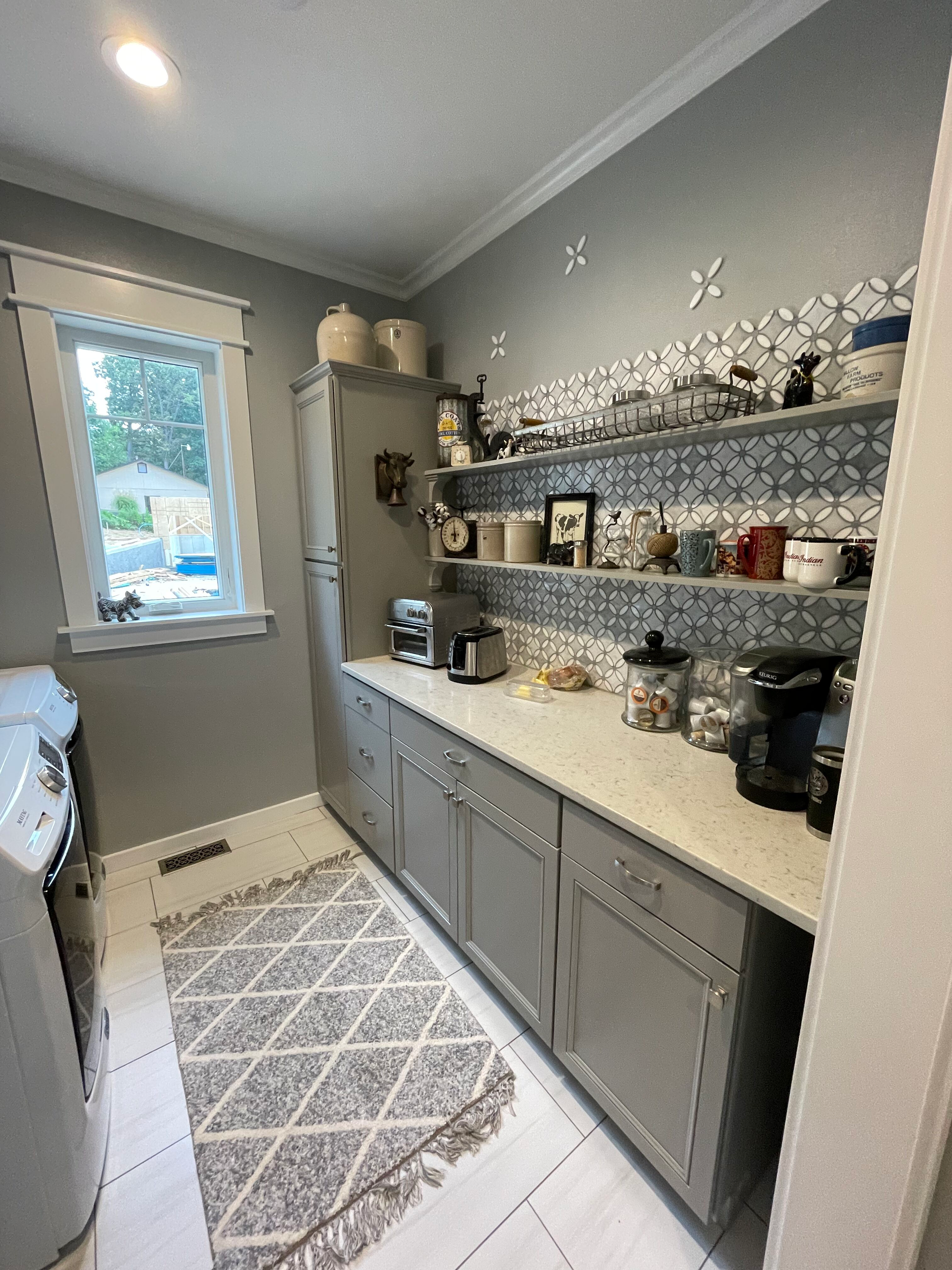 A kitchen with gray cabinets , white counter tops , and a rug.