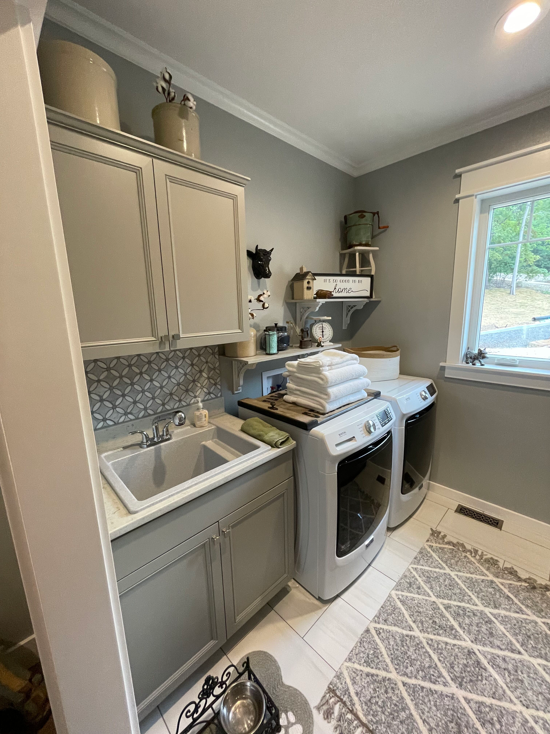A laundry room with a sink , washer and dryer , and a window.