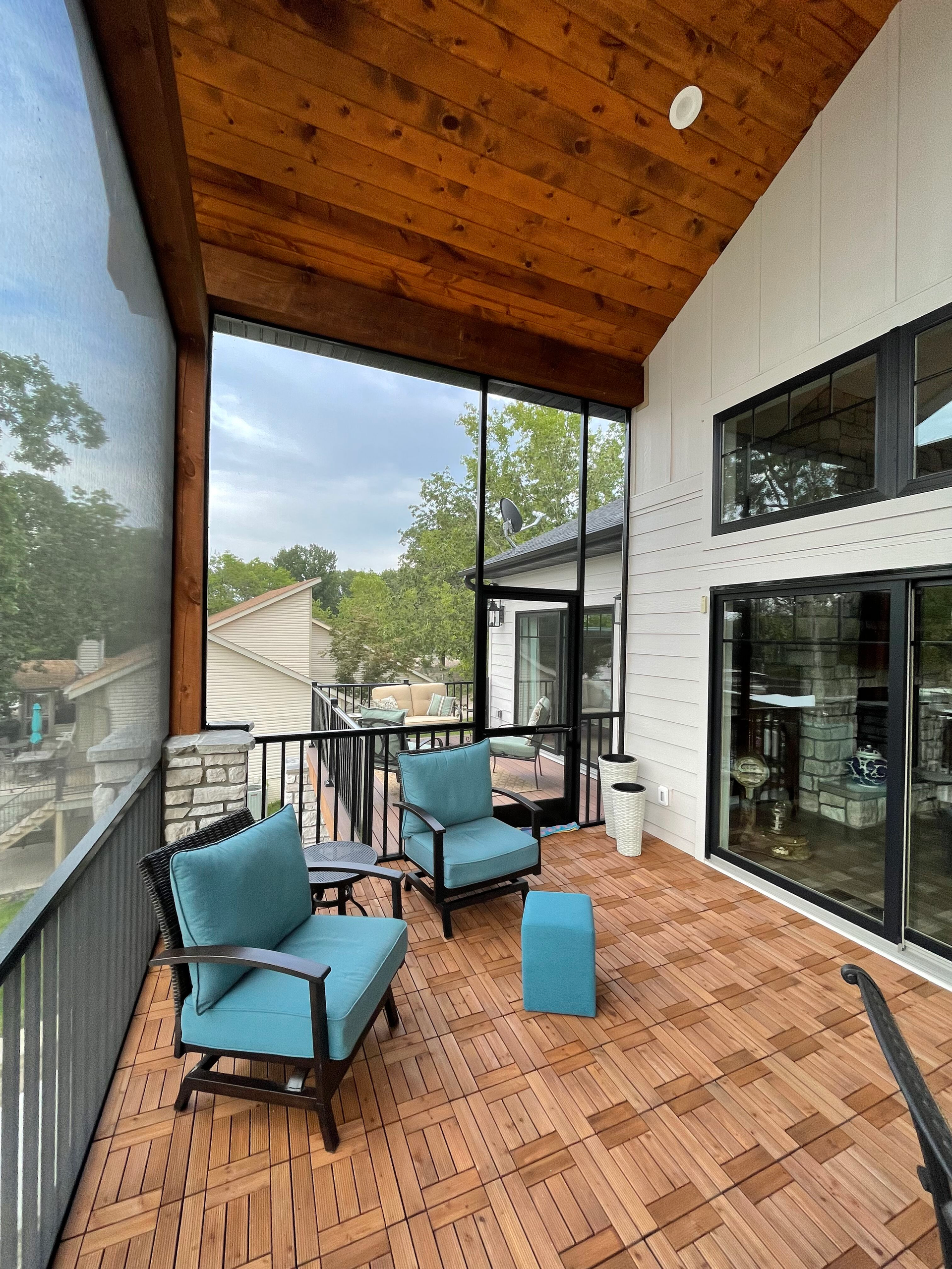 A screened in porch with two chairs and a table.
