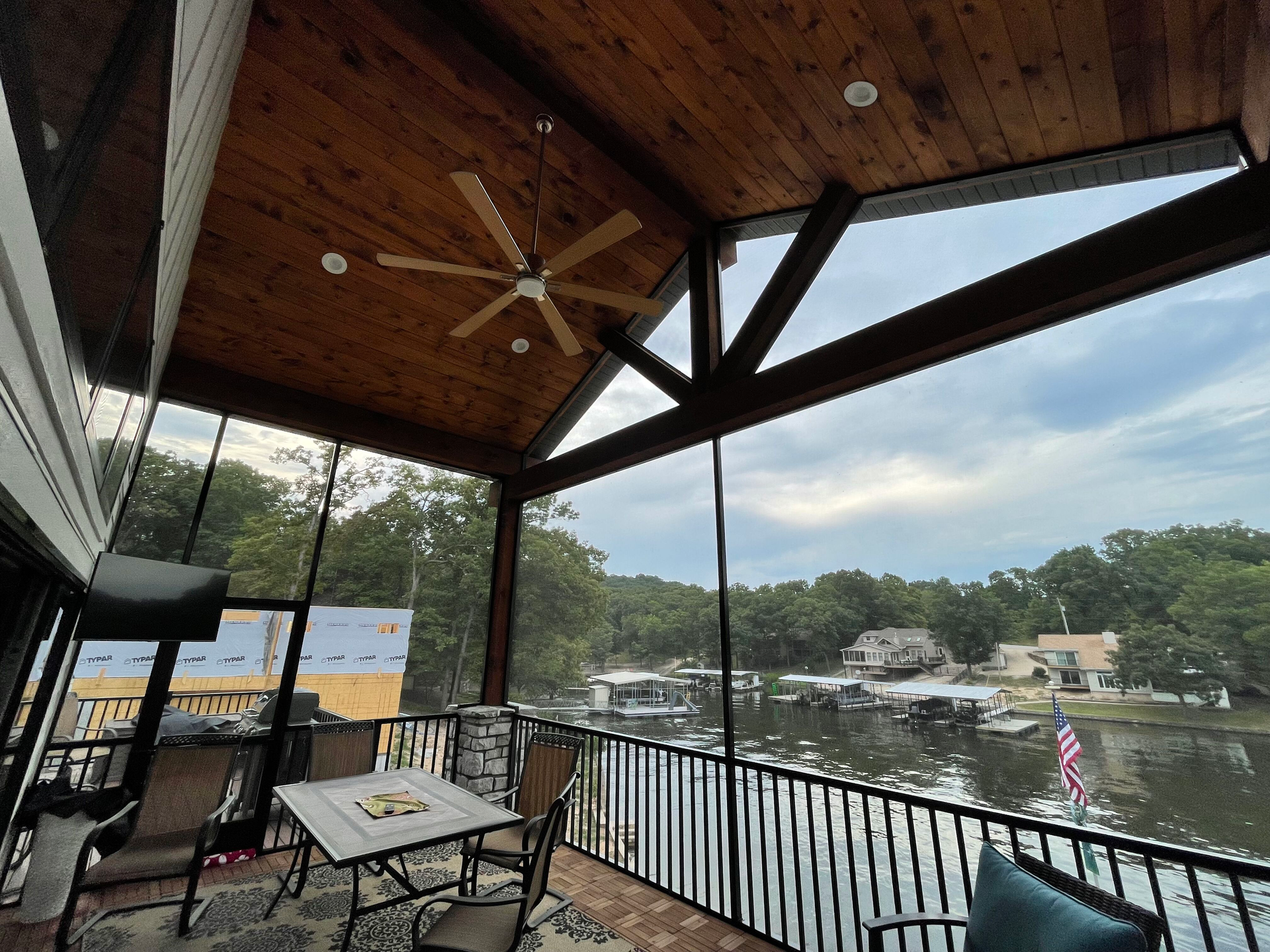 A screened in porch with a ceiling fan and a view of a lake.