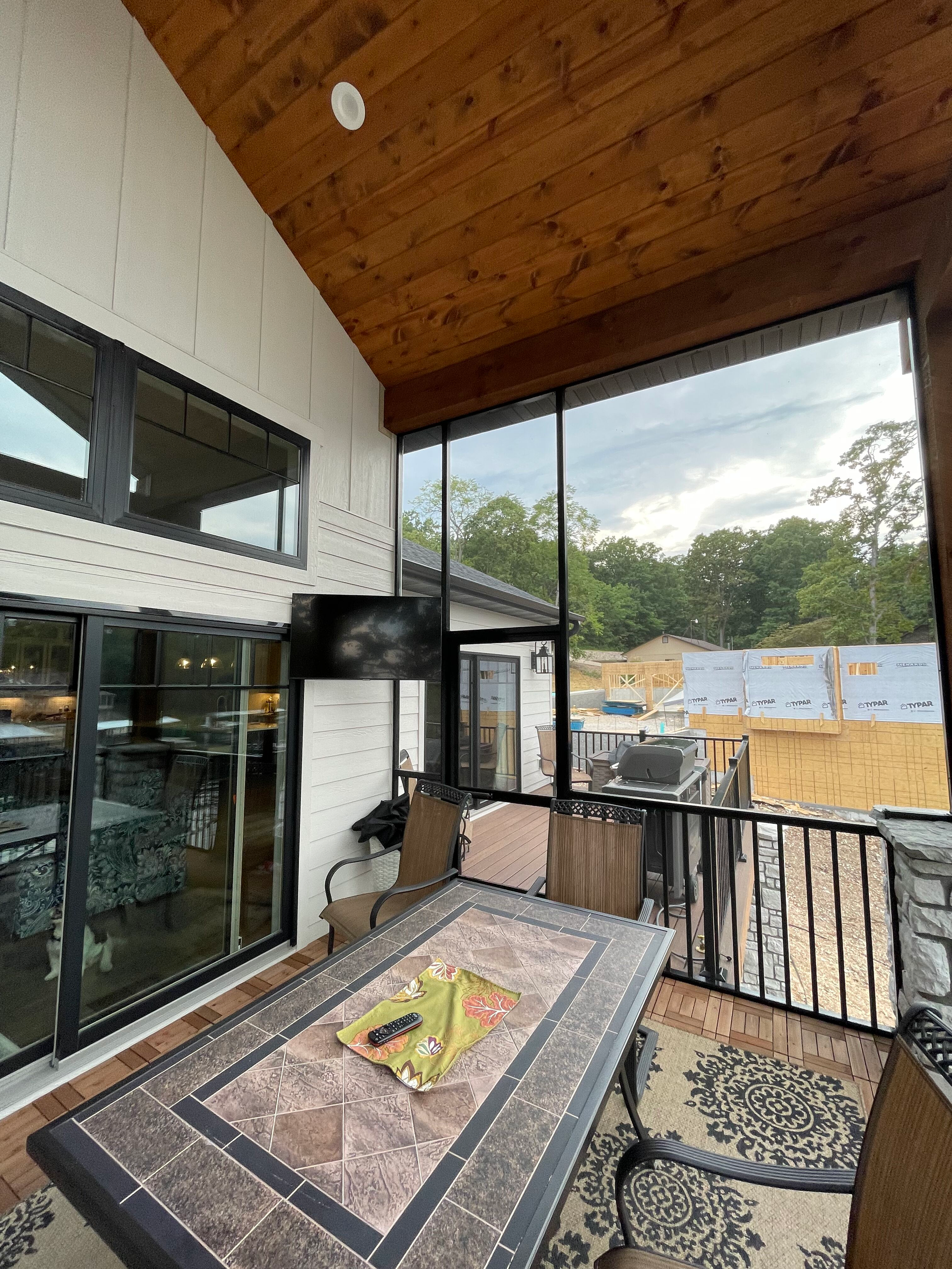 A screened in porch with a table and chairs and a large window.