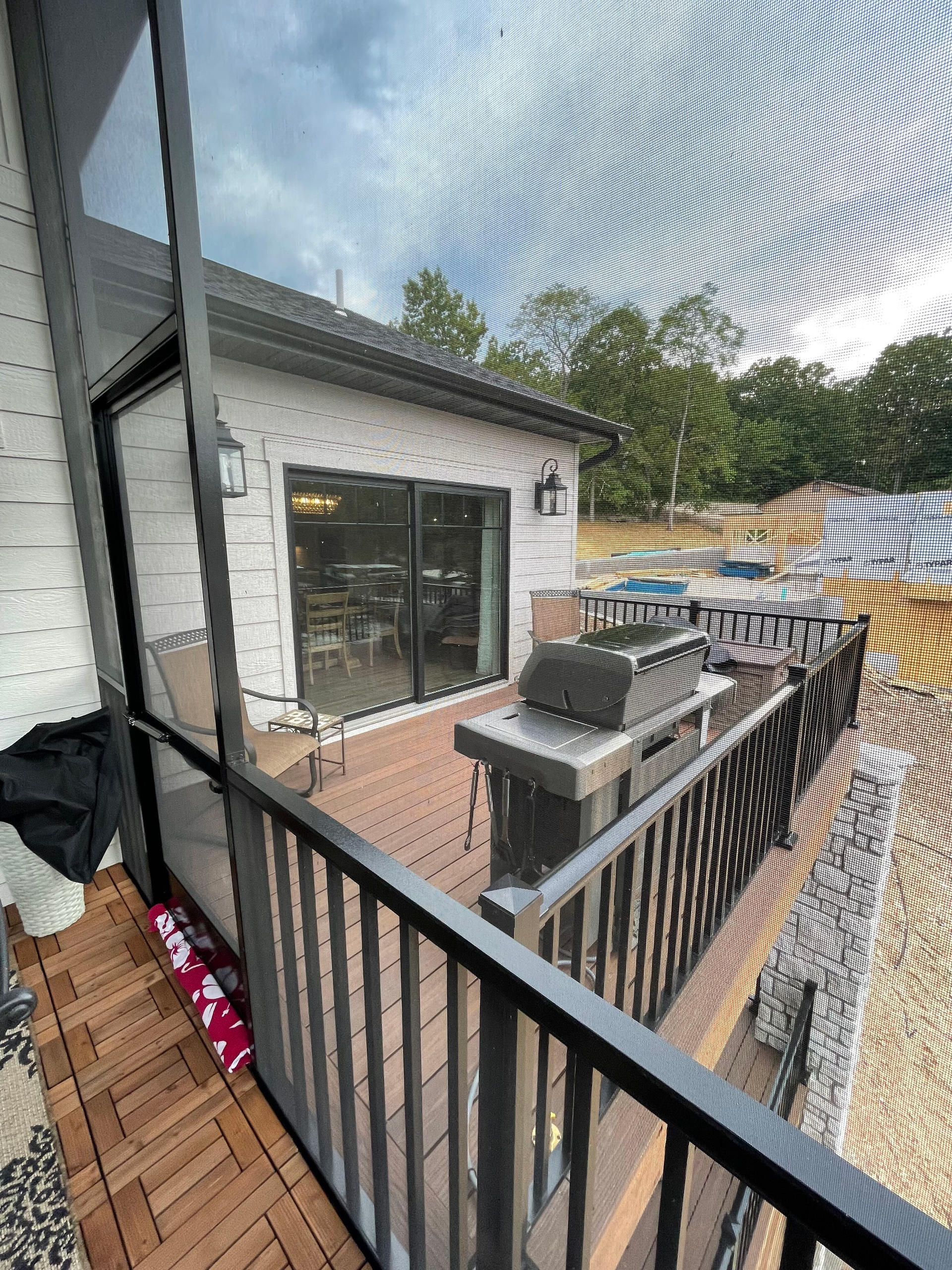 A view of a house from a balcony with a grill.