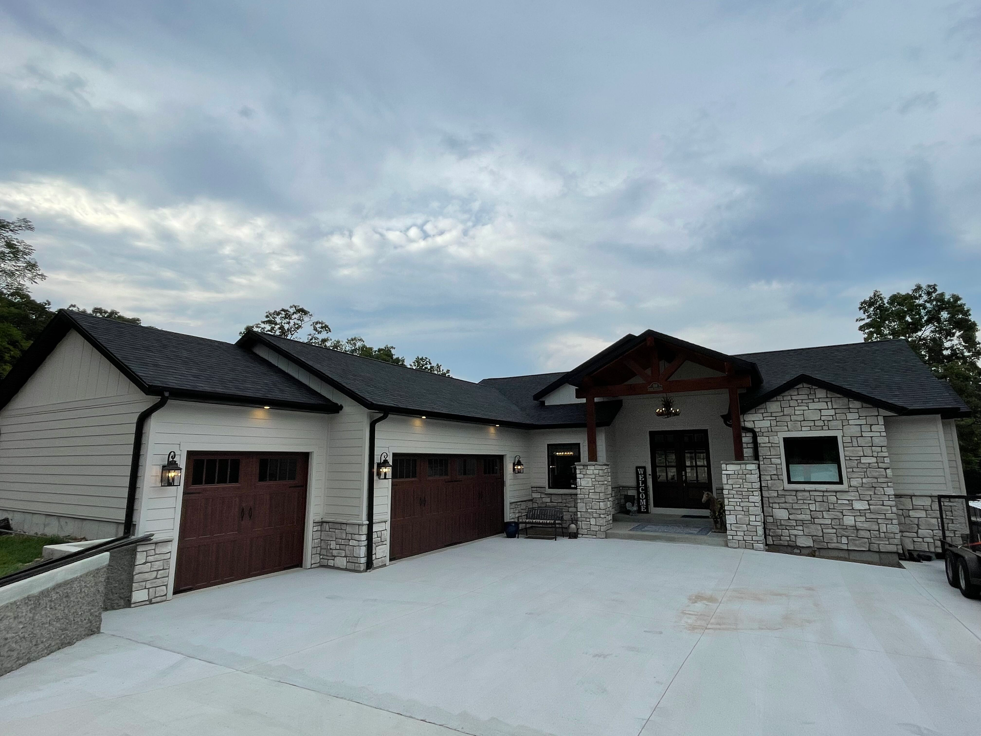 A large white house with a gray roof and brown garage doors.