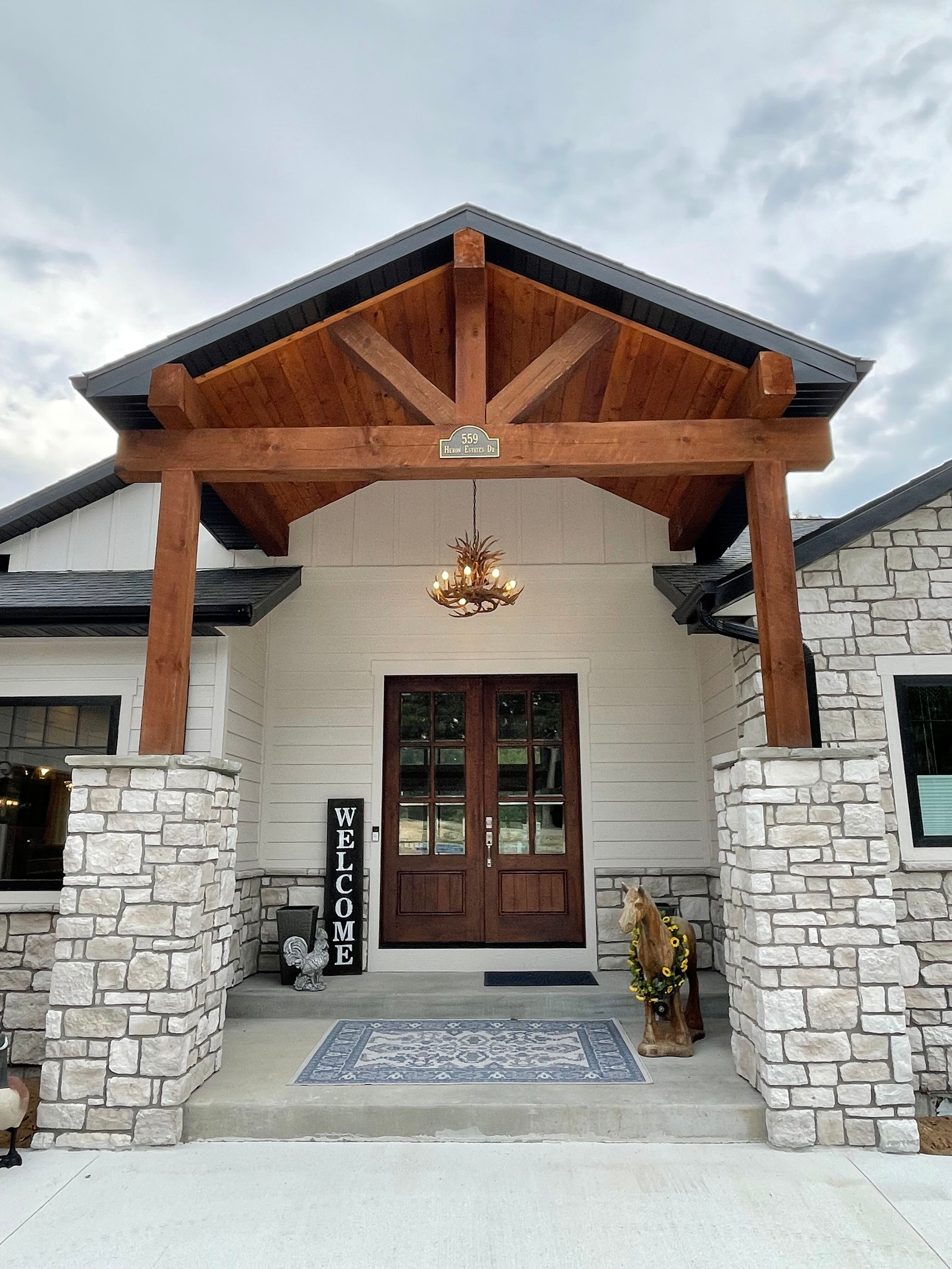 The front of a house with a wooden porch and a chandelier hanging from the ceiling.