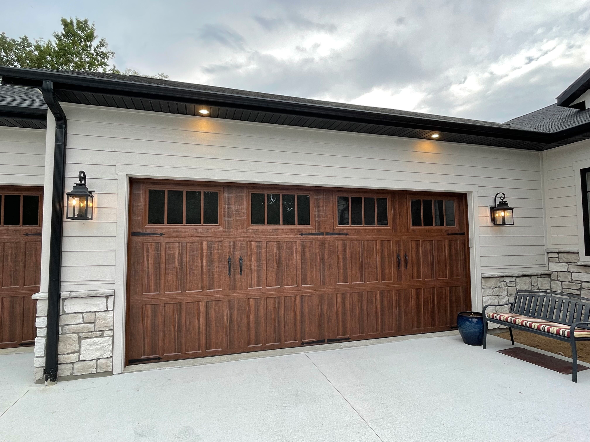A large wooden garage door is sitting in front of a white house.
