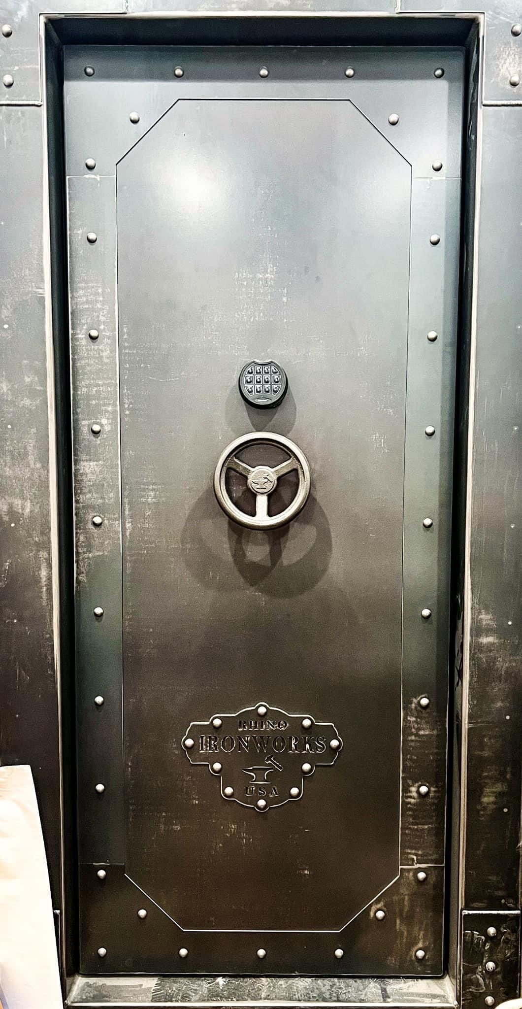 A close up of a metal door with a steering wheel on it.