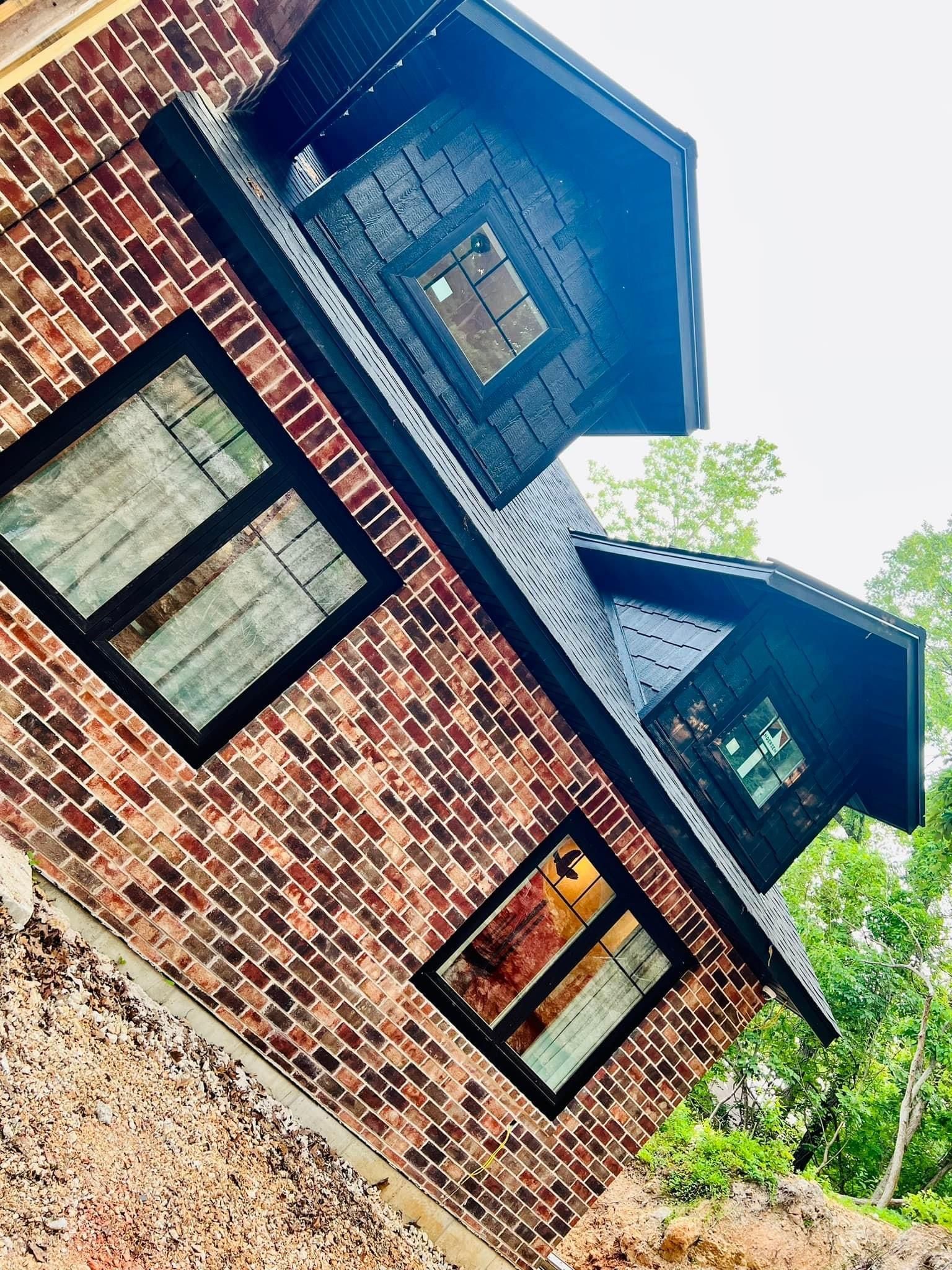 A brick house with black windows and a black roof.