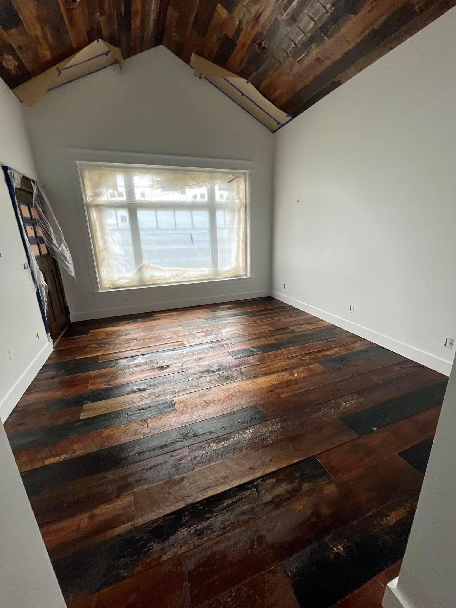 An empty room with a wooden floor and a window.