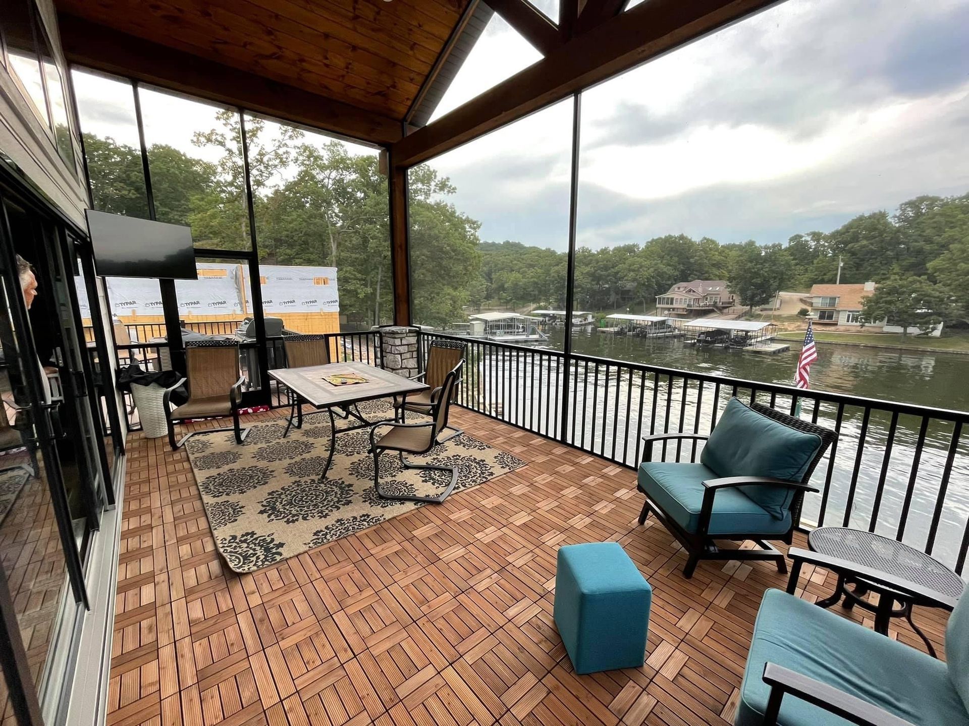 A screened in porch with a table and chairs overlooking a lake.