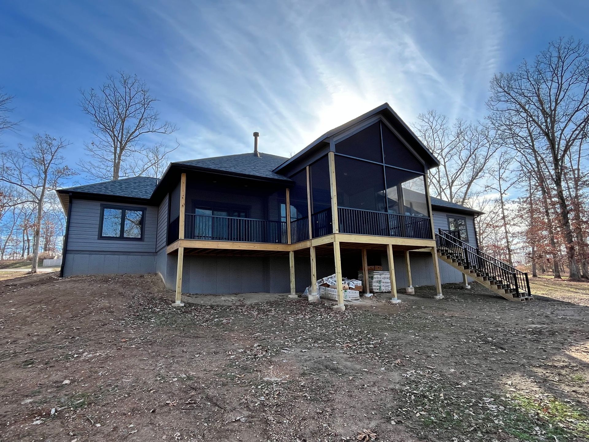 The back of a house with a screened in porch and stairs.