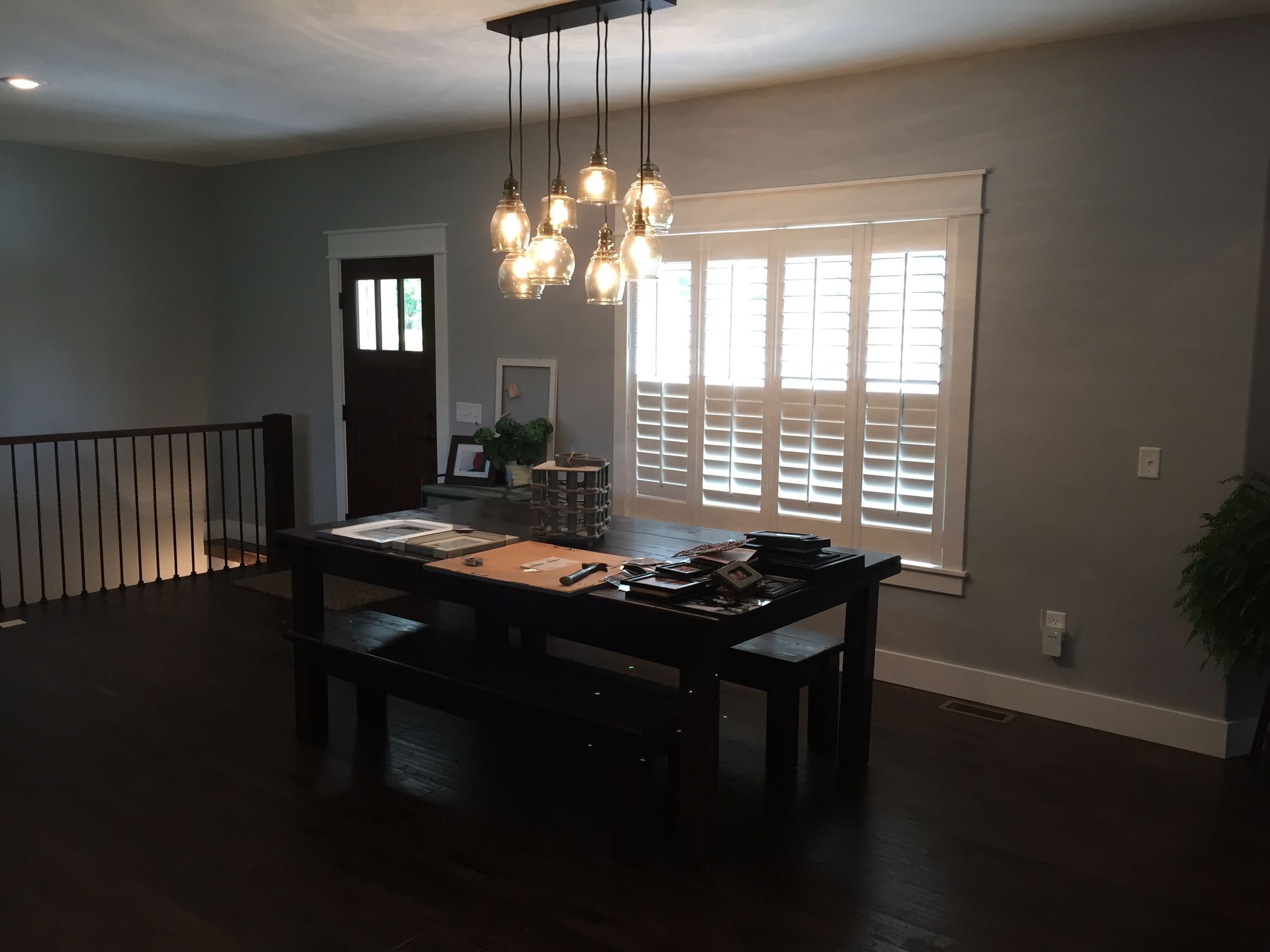 A dining room with a table and chairs and a window with shutters