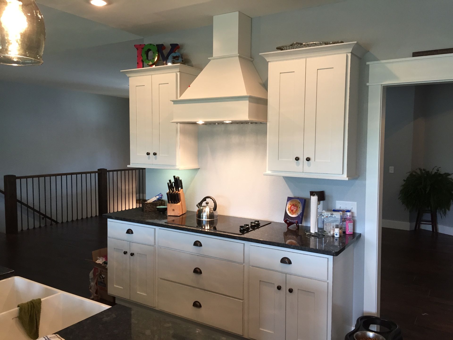 A kitchen with white cabinets , black counter tops , and a stove top oven.