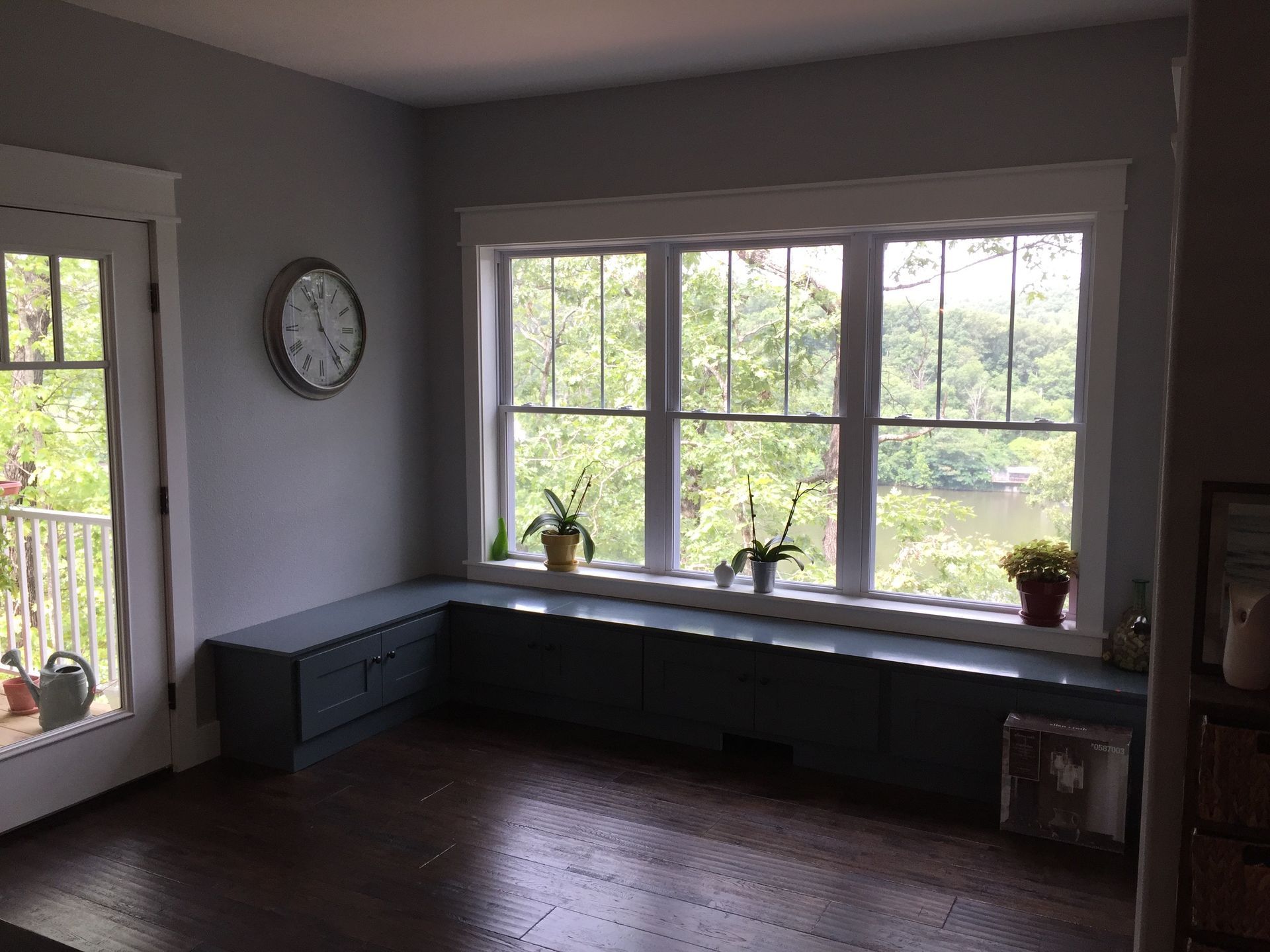 A living room with a window seat and a clock on the wall.