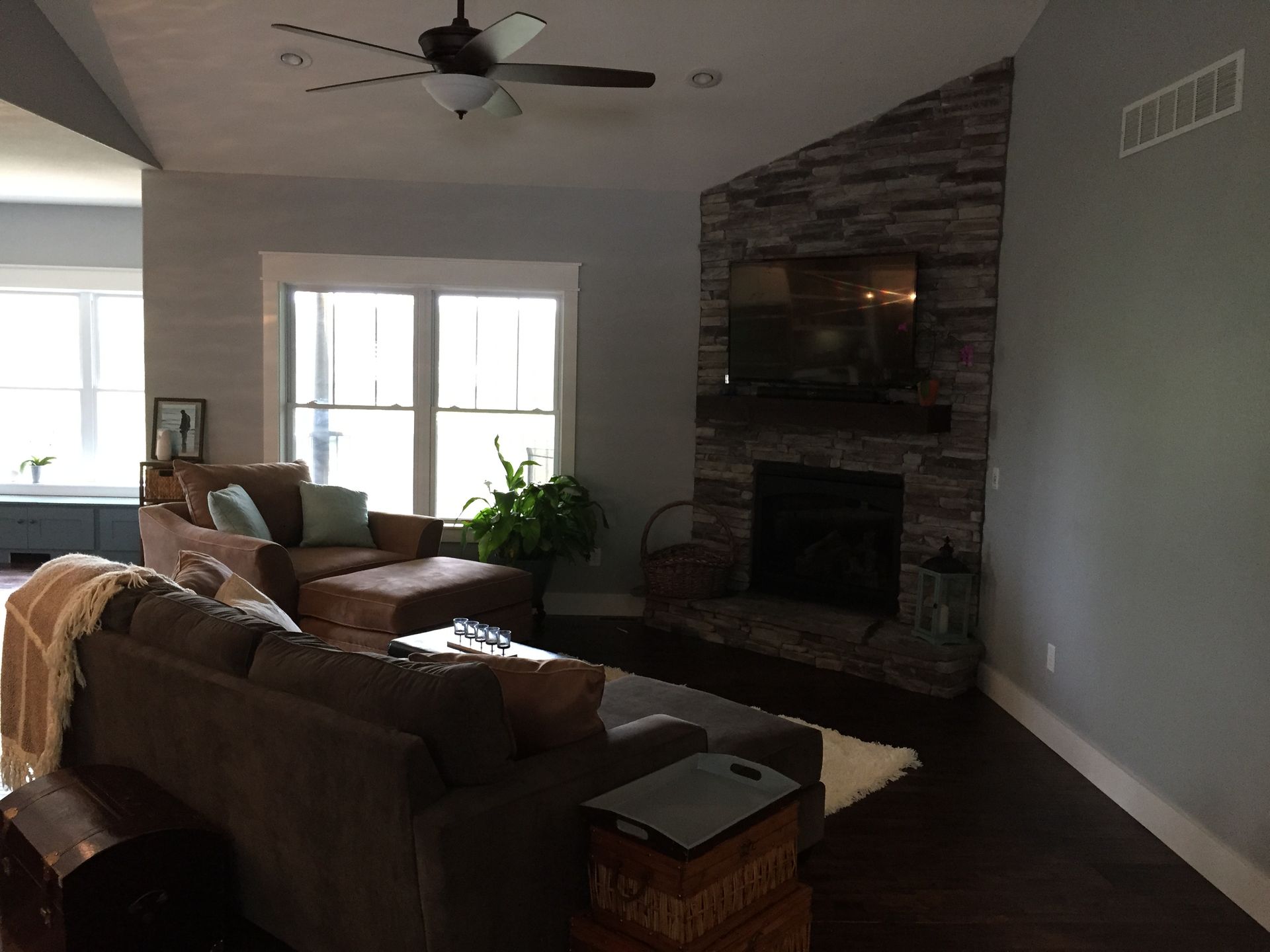 A living room with a fireplace and a ceiling fan