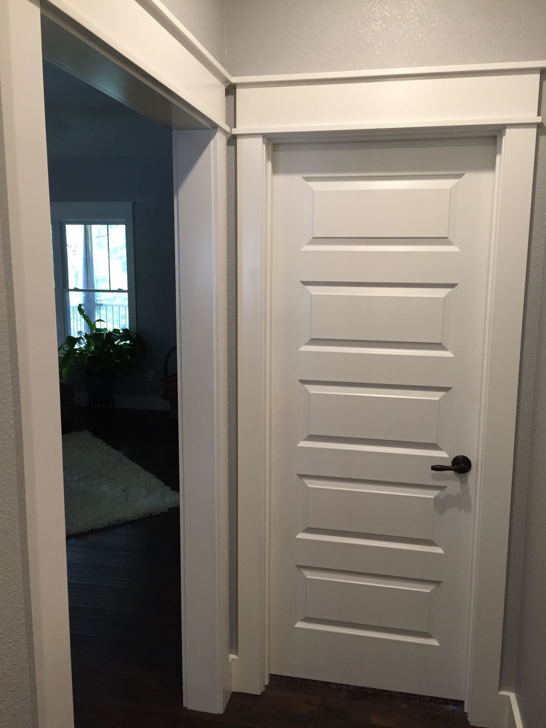 A white door in a hallway leading to a living room.