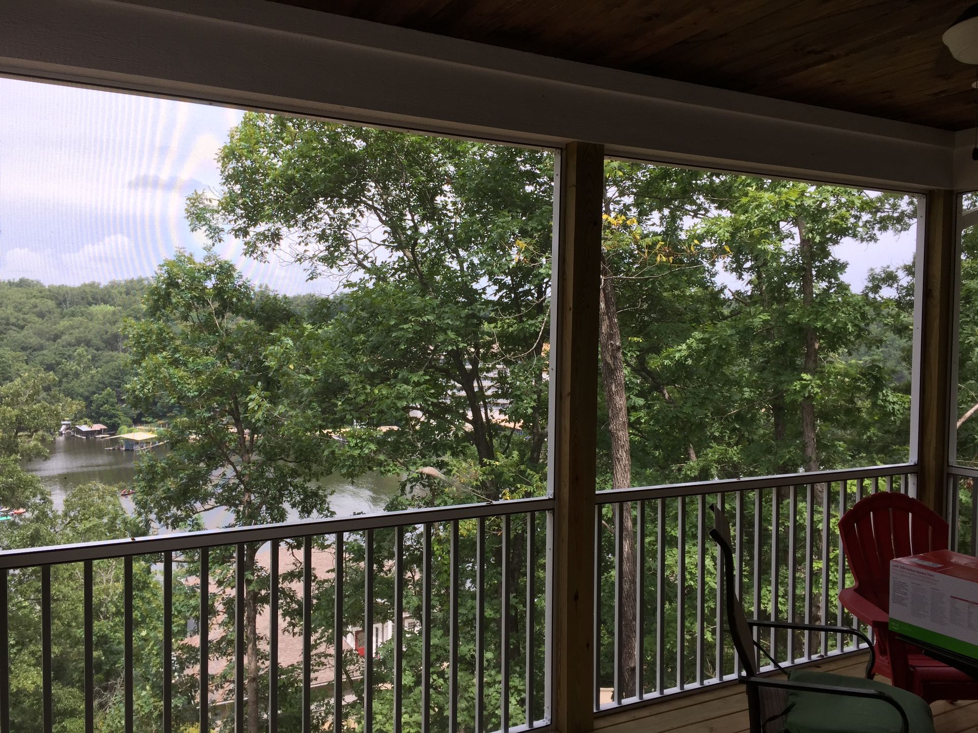 A screened in porch with a view of a lake and trees