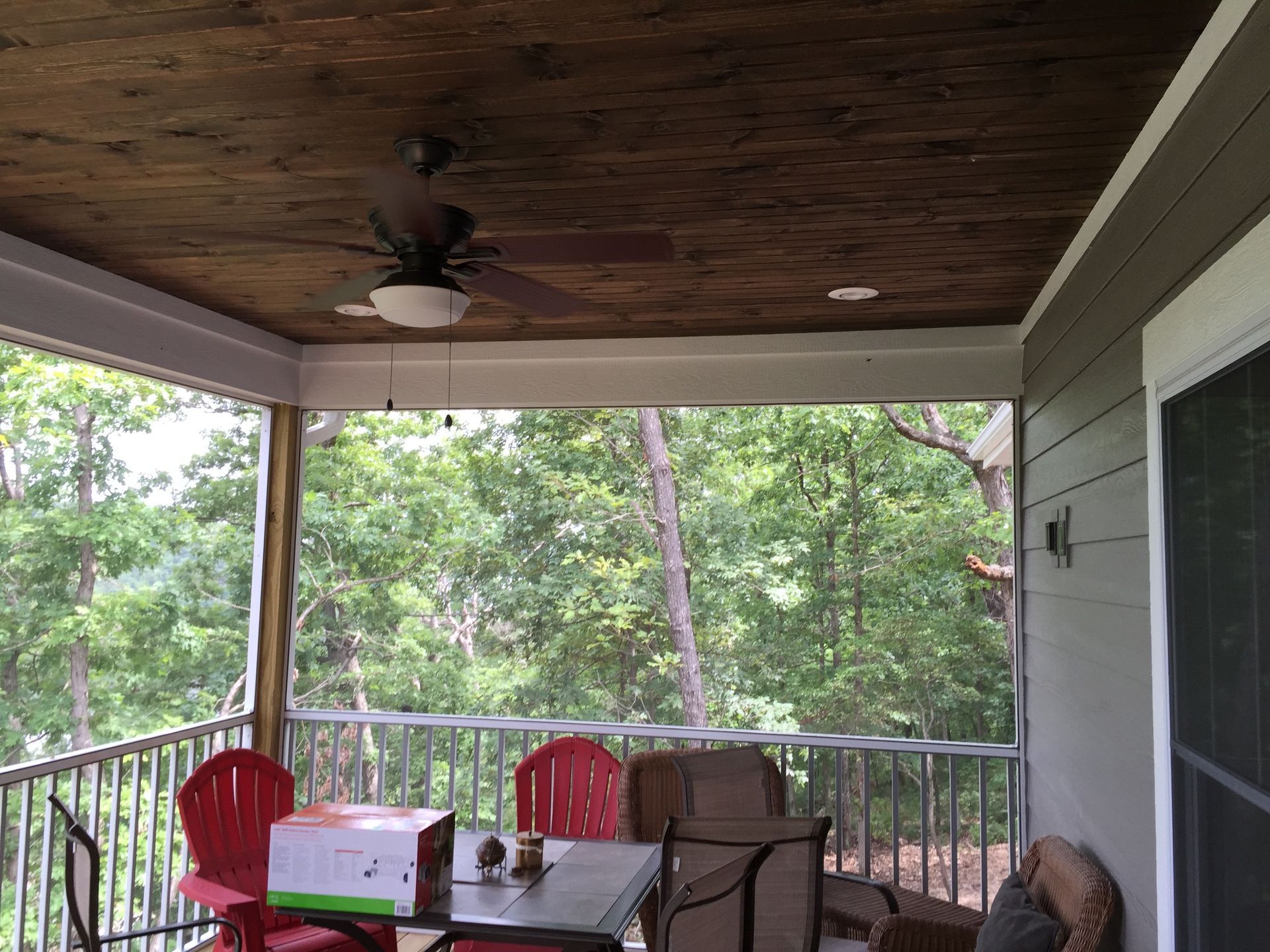 A porch with a table and chairs and a ceiling fan.