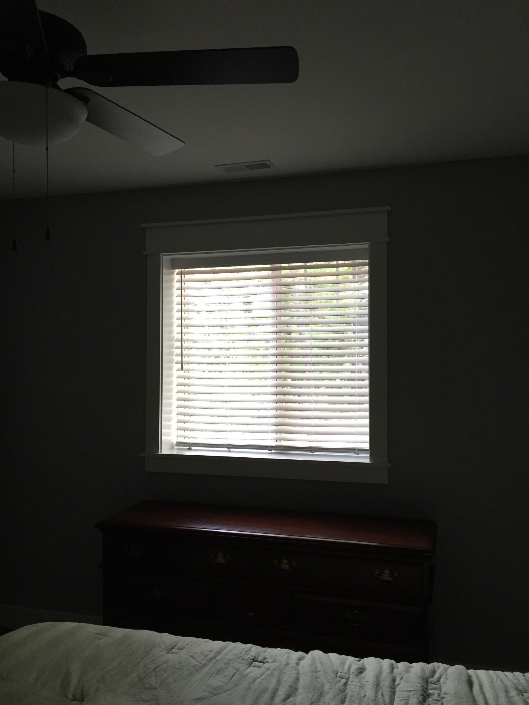 A bedroom with a window and a ceiling fan
