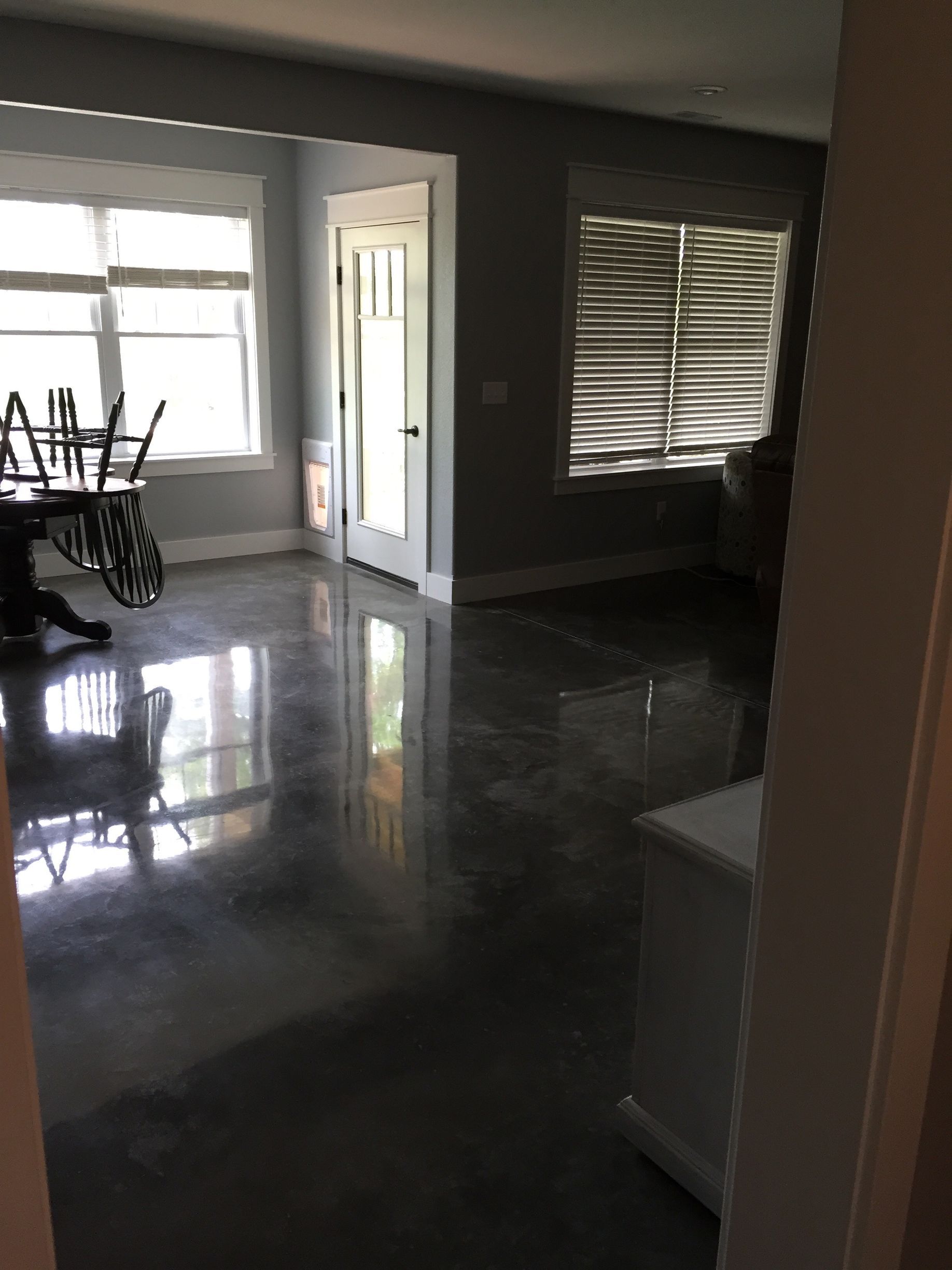 A living room with a table and chairs and a shiny concrete floor.