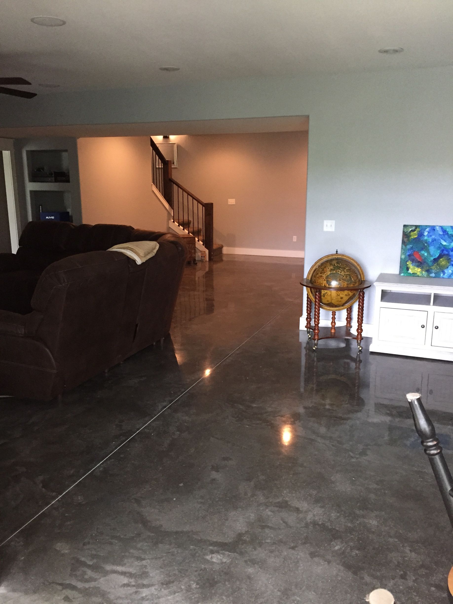 A living room with a couch , chairs , a globe and a staircase.