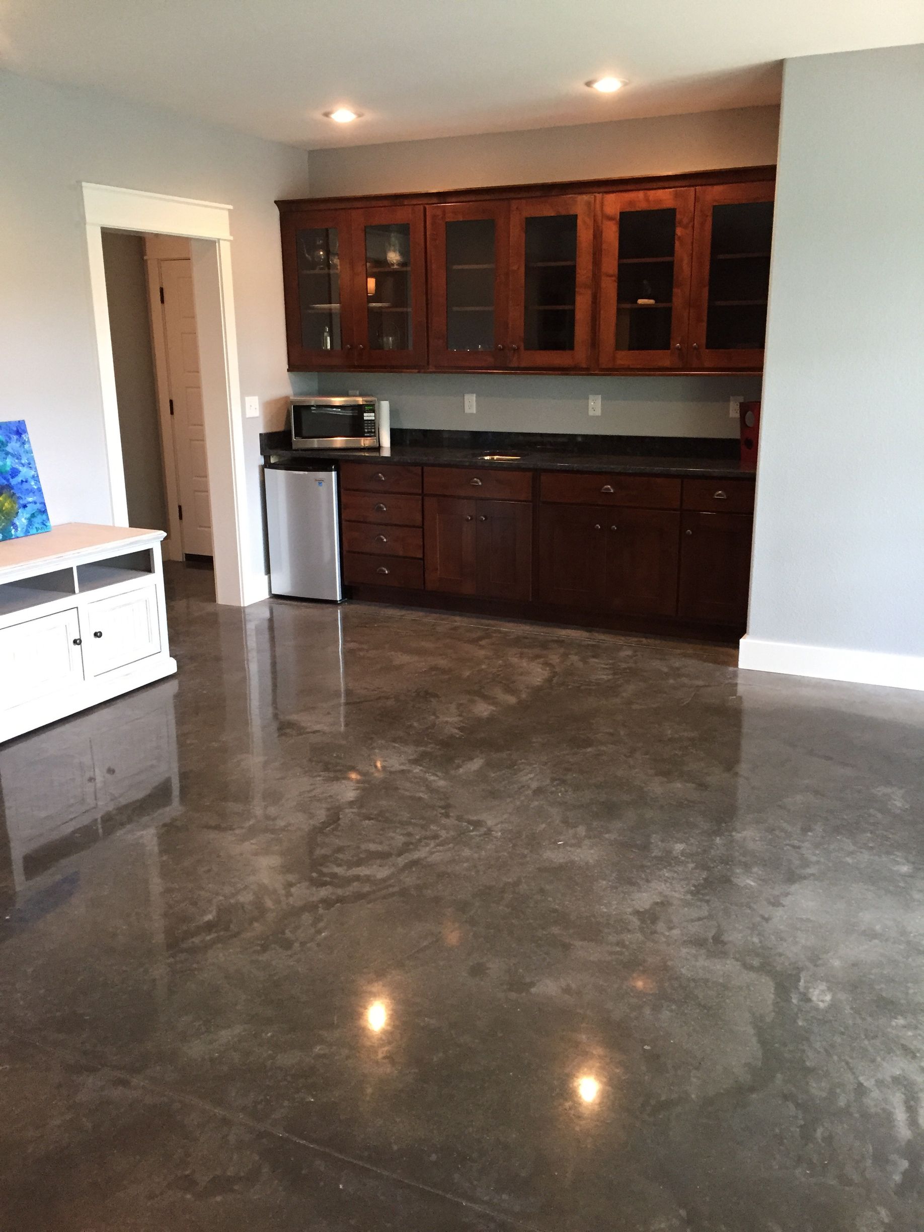 A kitchen with wooden cabinets and a shiny concrete floor