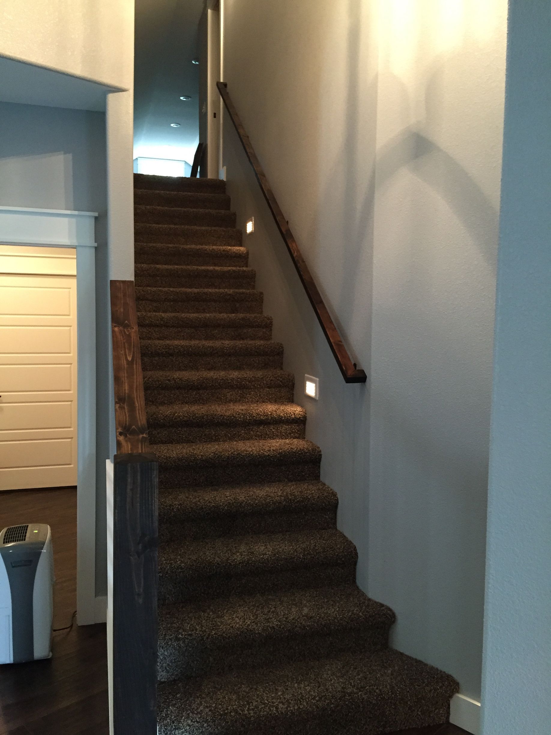A staircase with a wooden railing and carpeted steps