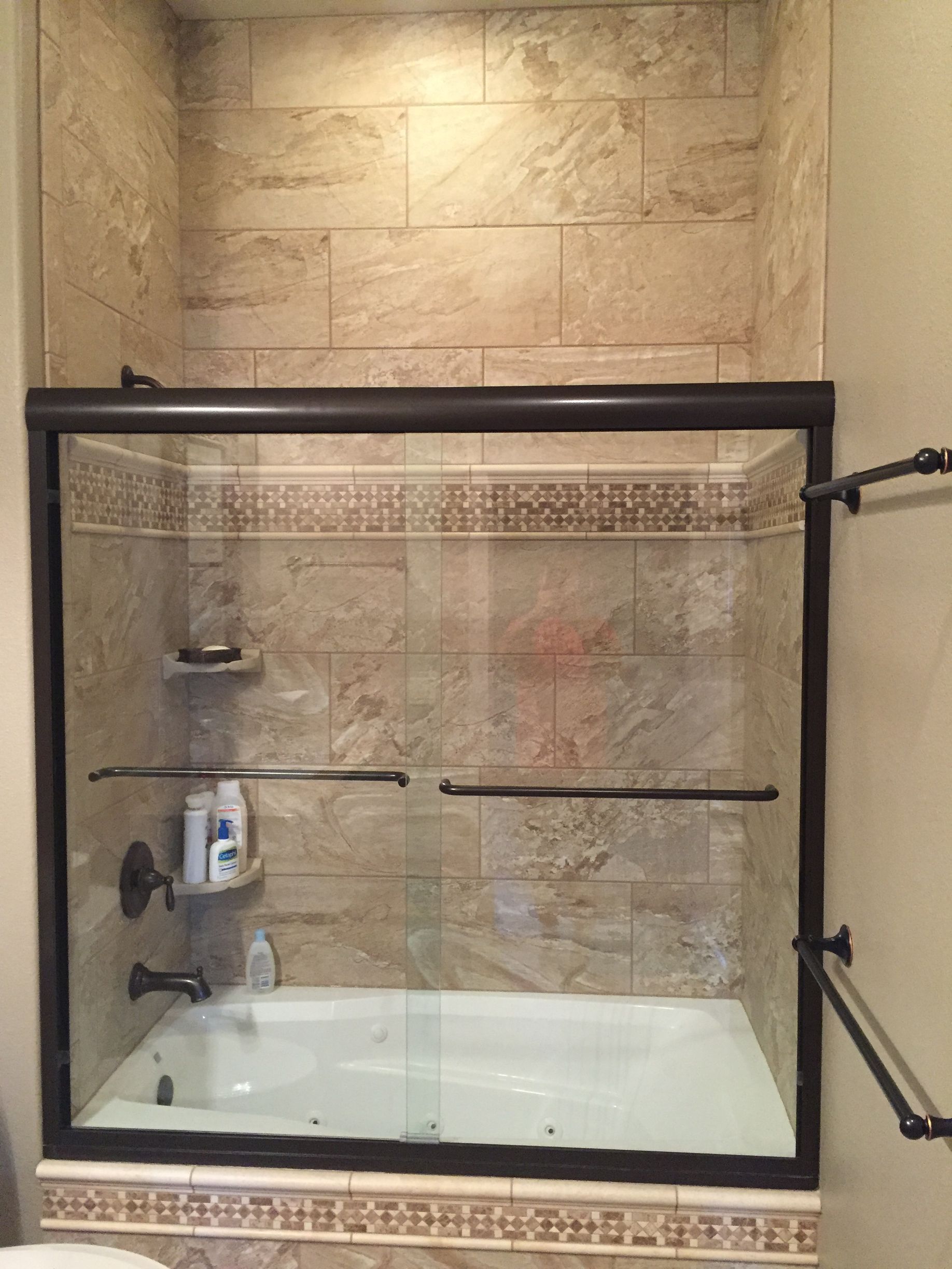 There is a bathtub in the shower with a glass door.