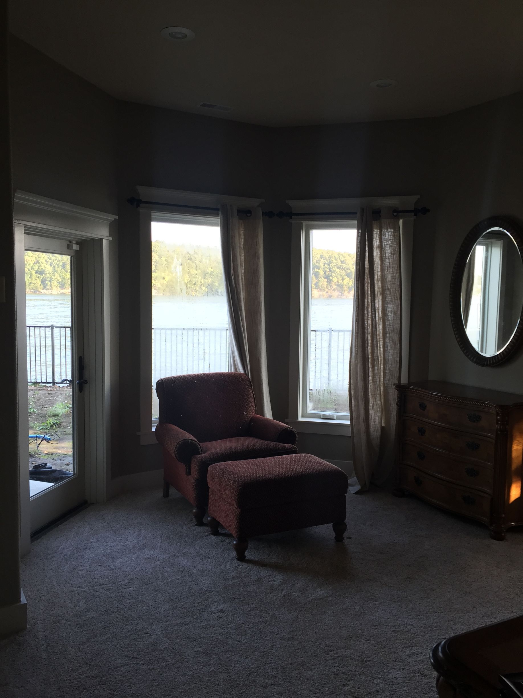 A living room with a chair and ottoman and a mirror
