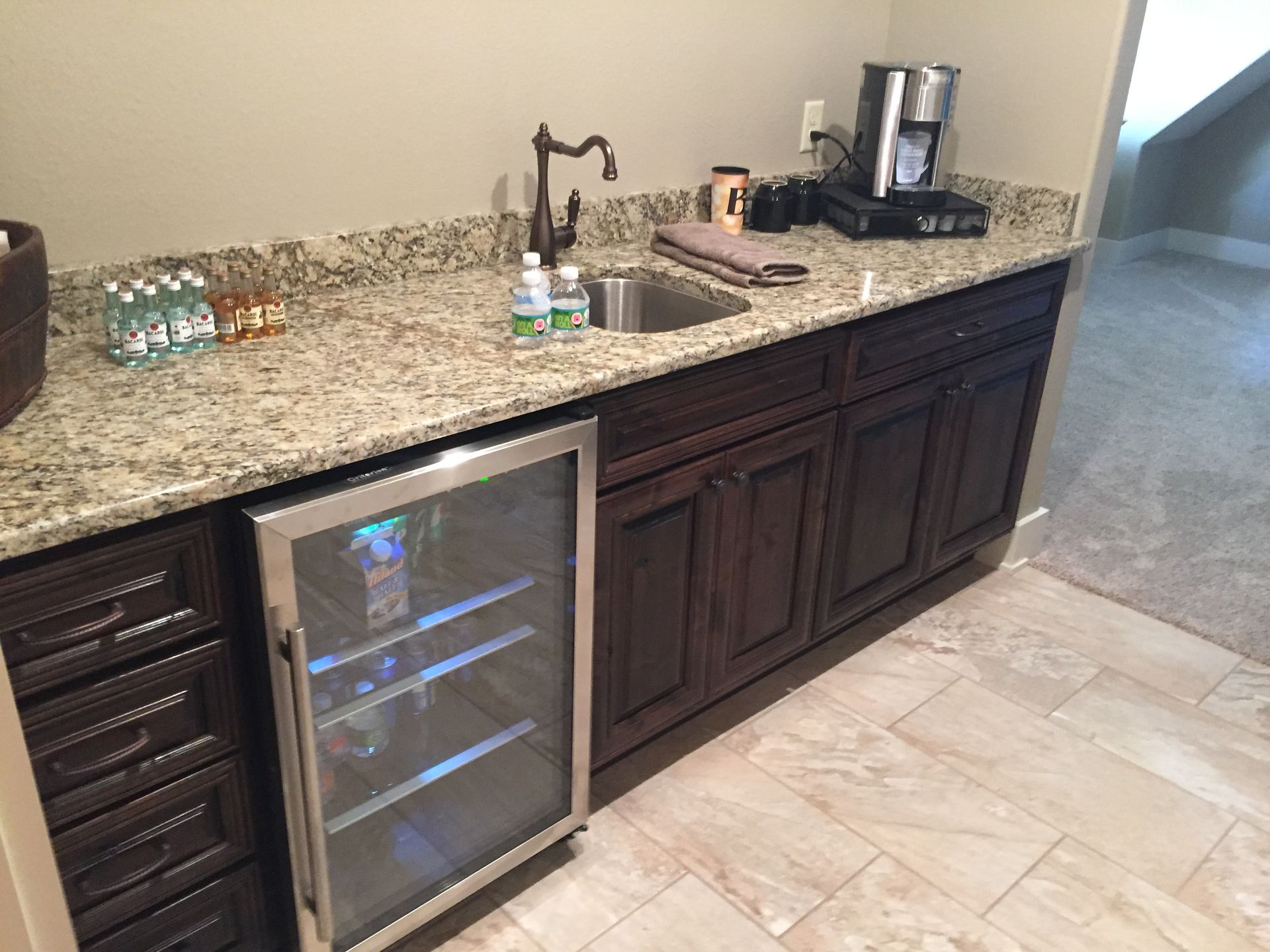 A kitchen with a sink , refrigerator , and coffee maker.