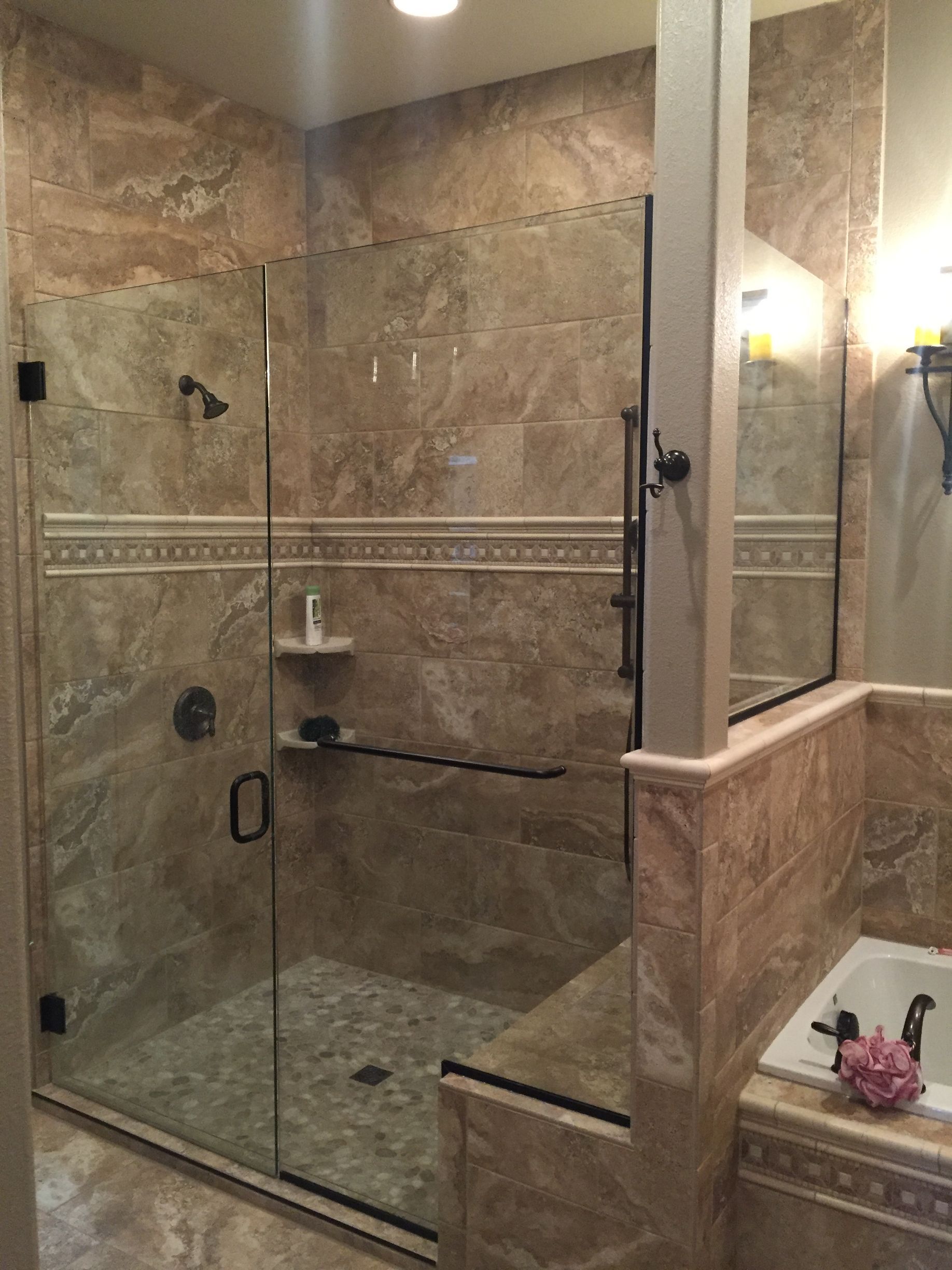 A bathroom with a walk in shower with a glass door.