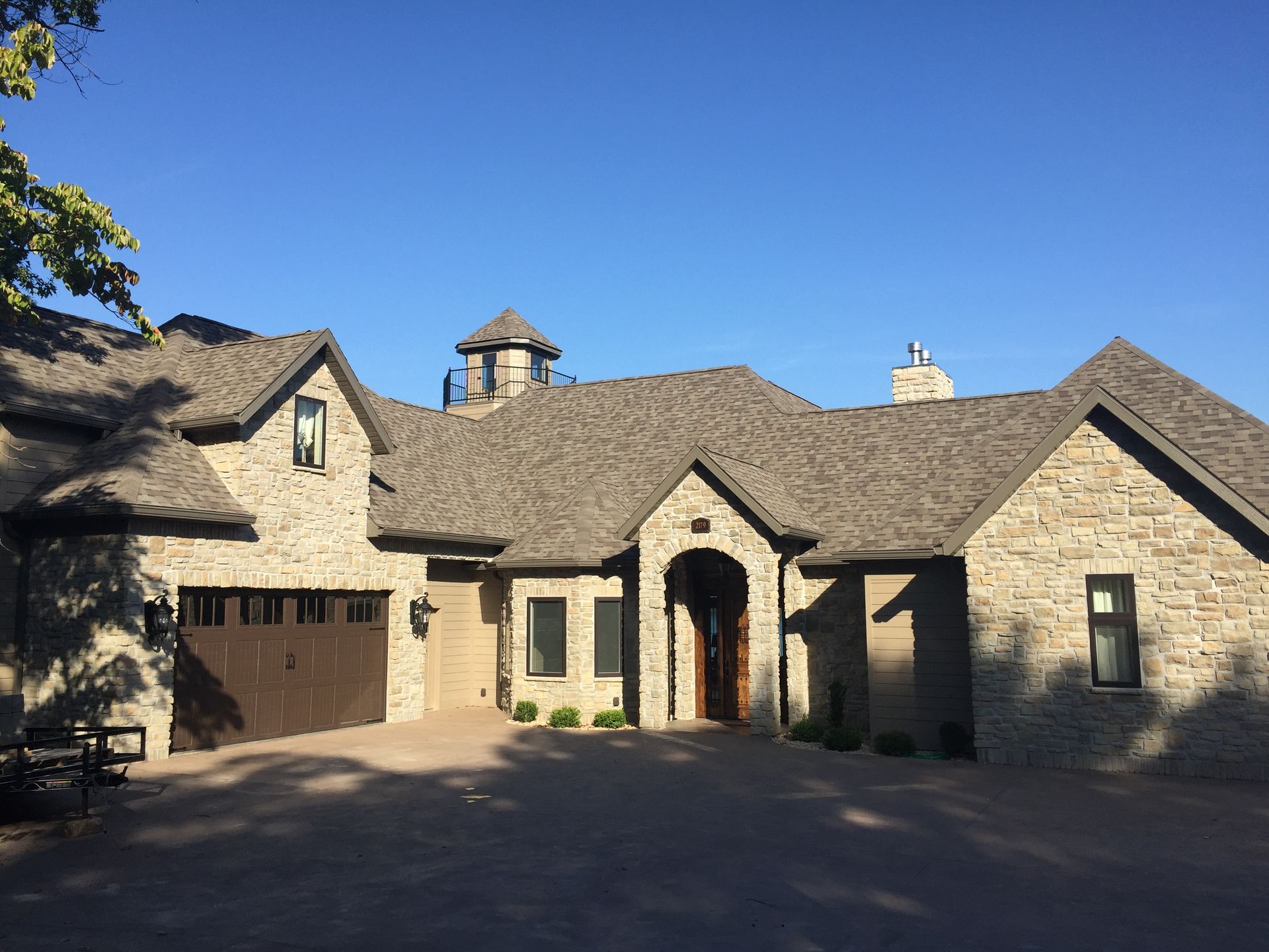 A large brick house with a garage and a blue sky in the background.