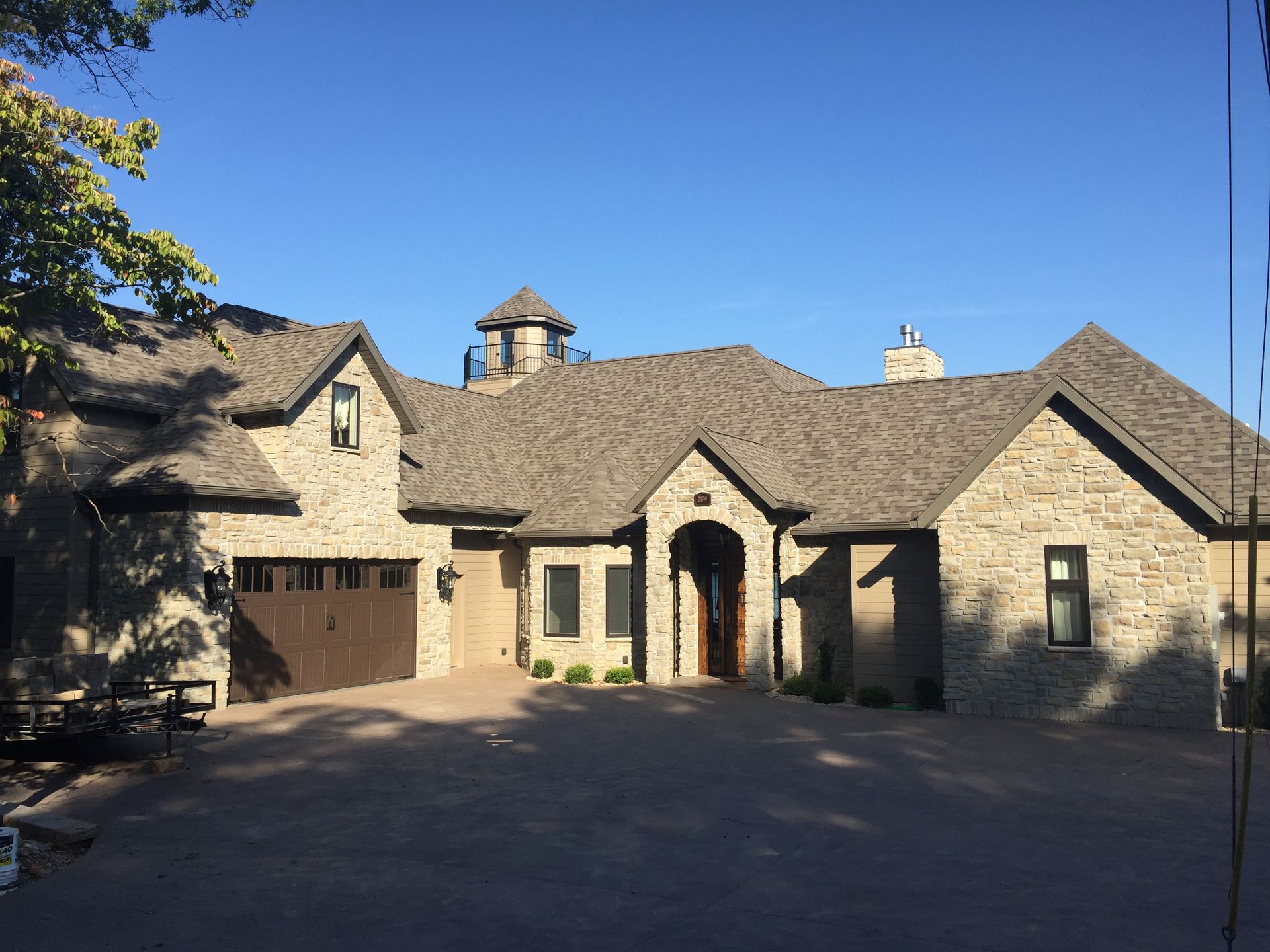 A large brick house with a garage and a blue sky in the background.