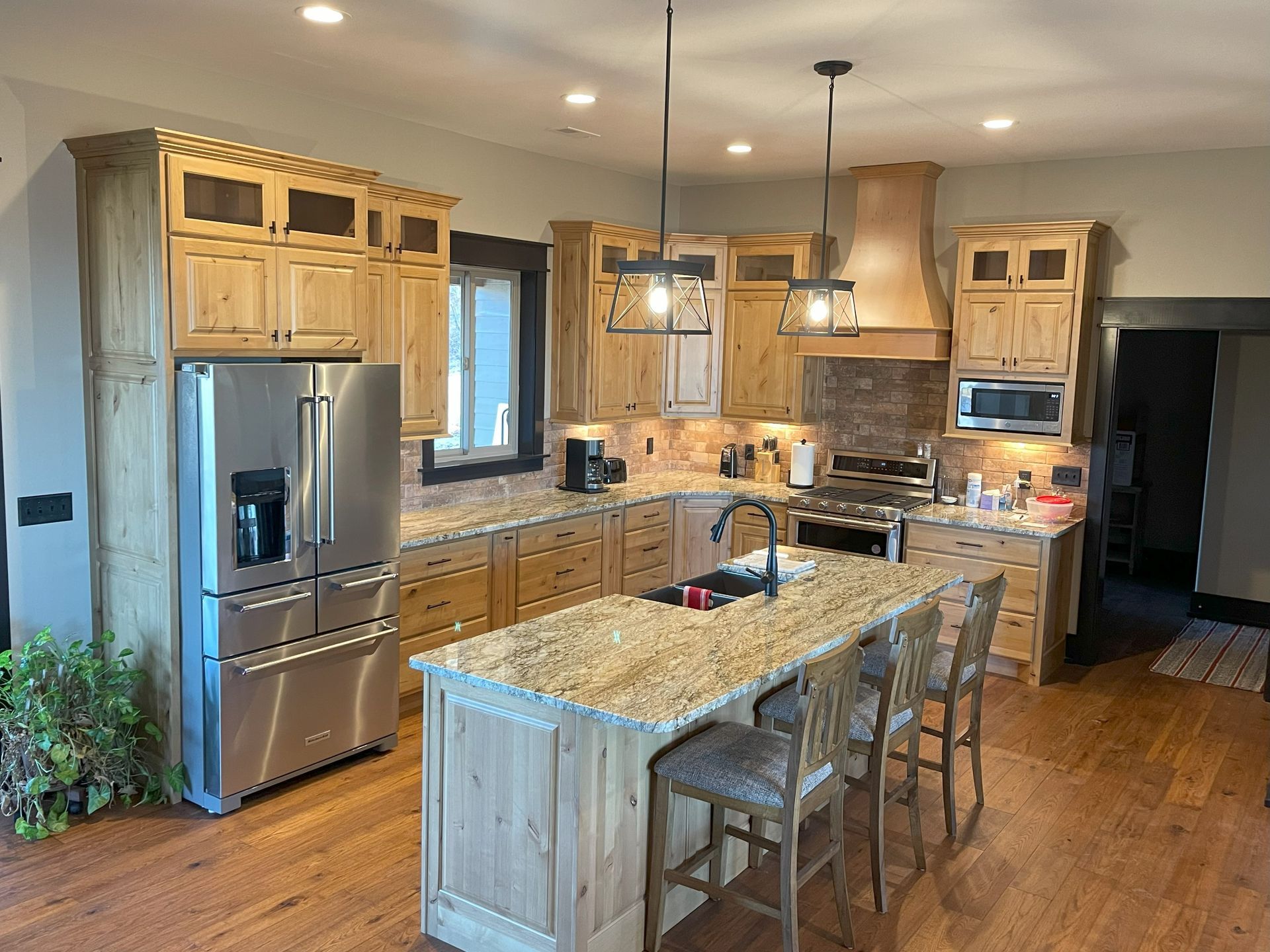 A kitchen with stainless steel appliances , granite counter tops , wooden cabinets and a large island.