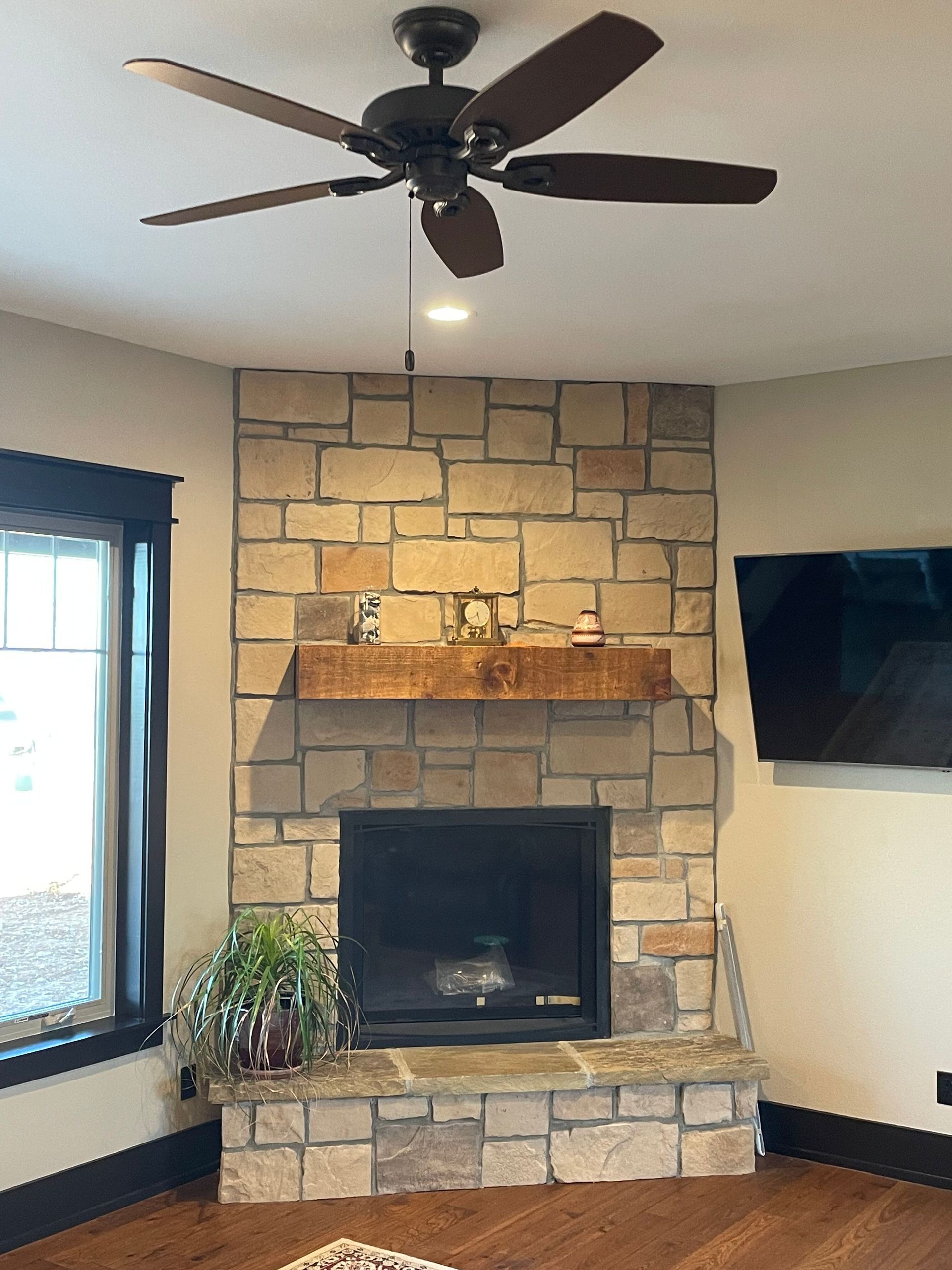 A living room with a fireplace and a ceiling fan