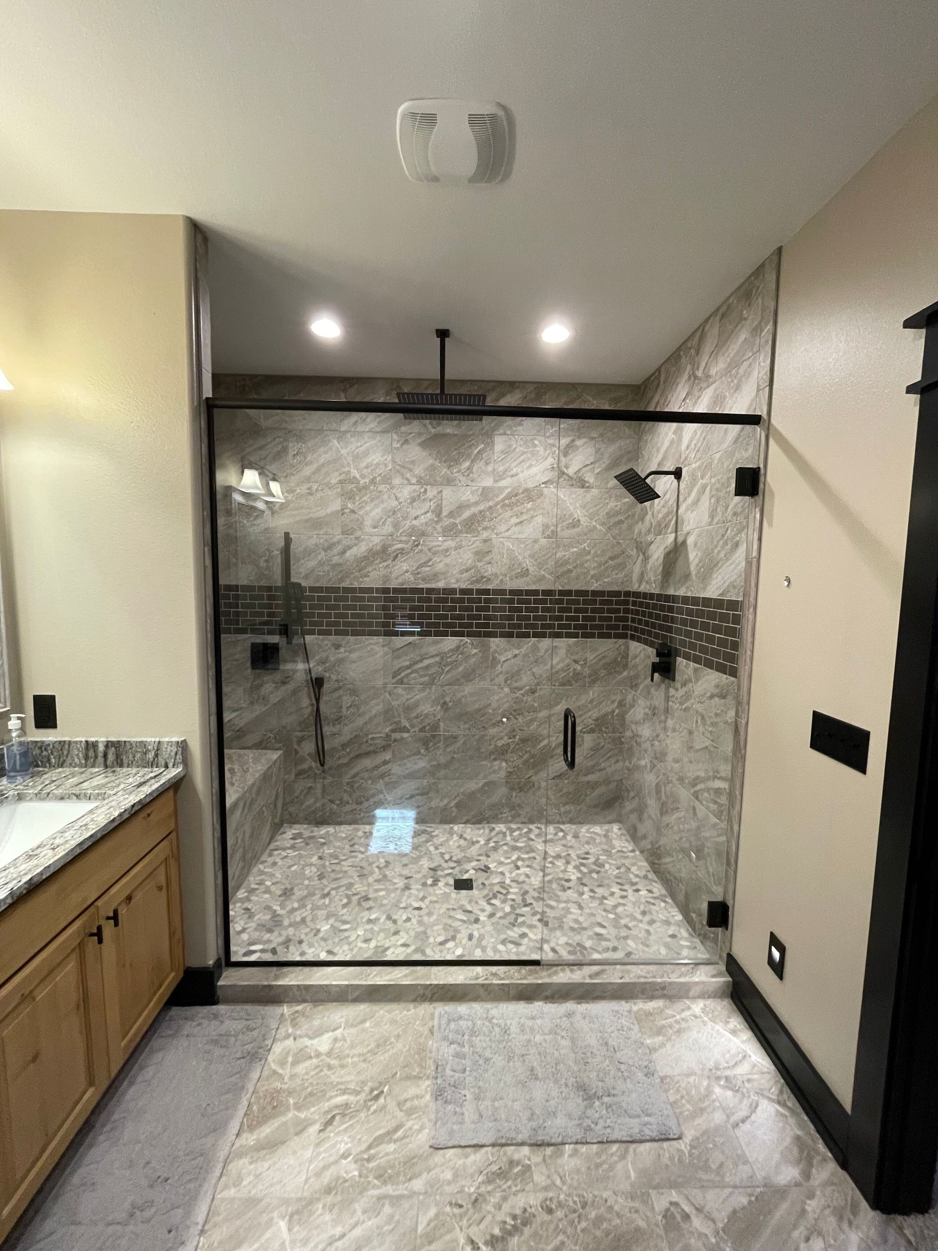 A bathroom with a walk in shower and a sink.