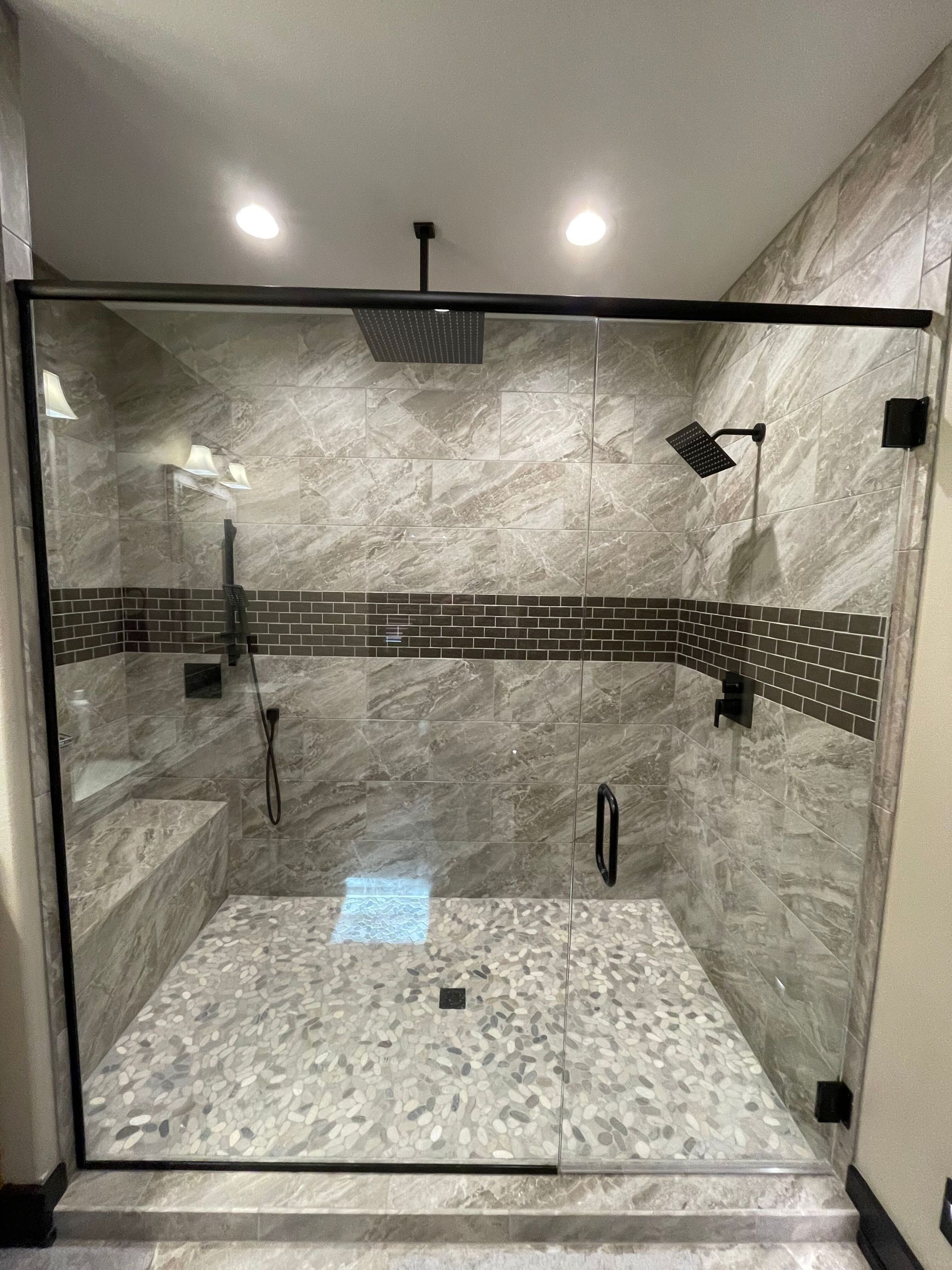 A bathroom with a walk in shower with a glass door and a shower head.