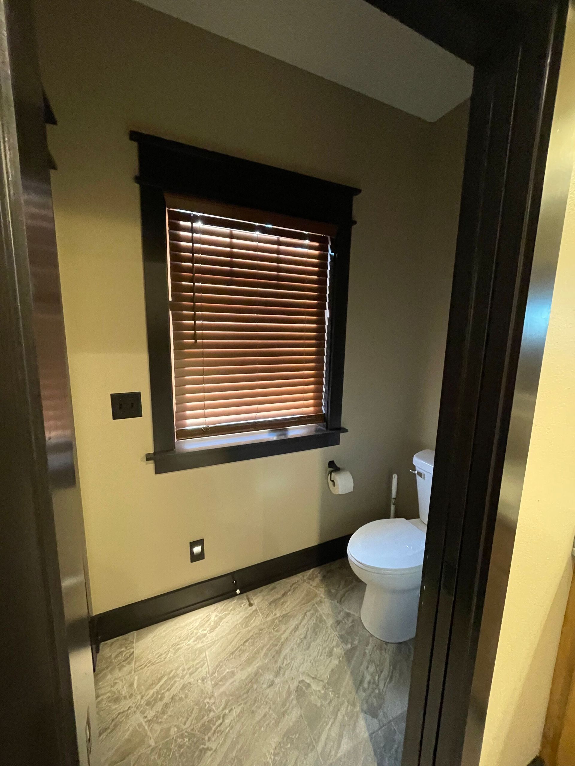 A bathroom with a toilet and a window with blinds