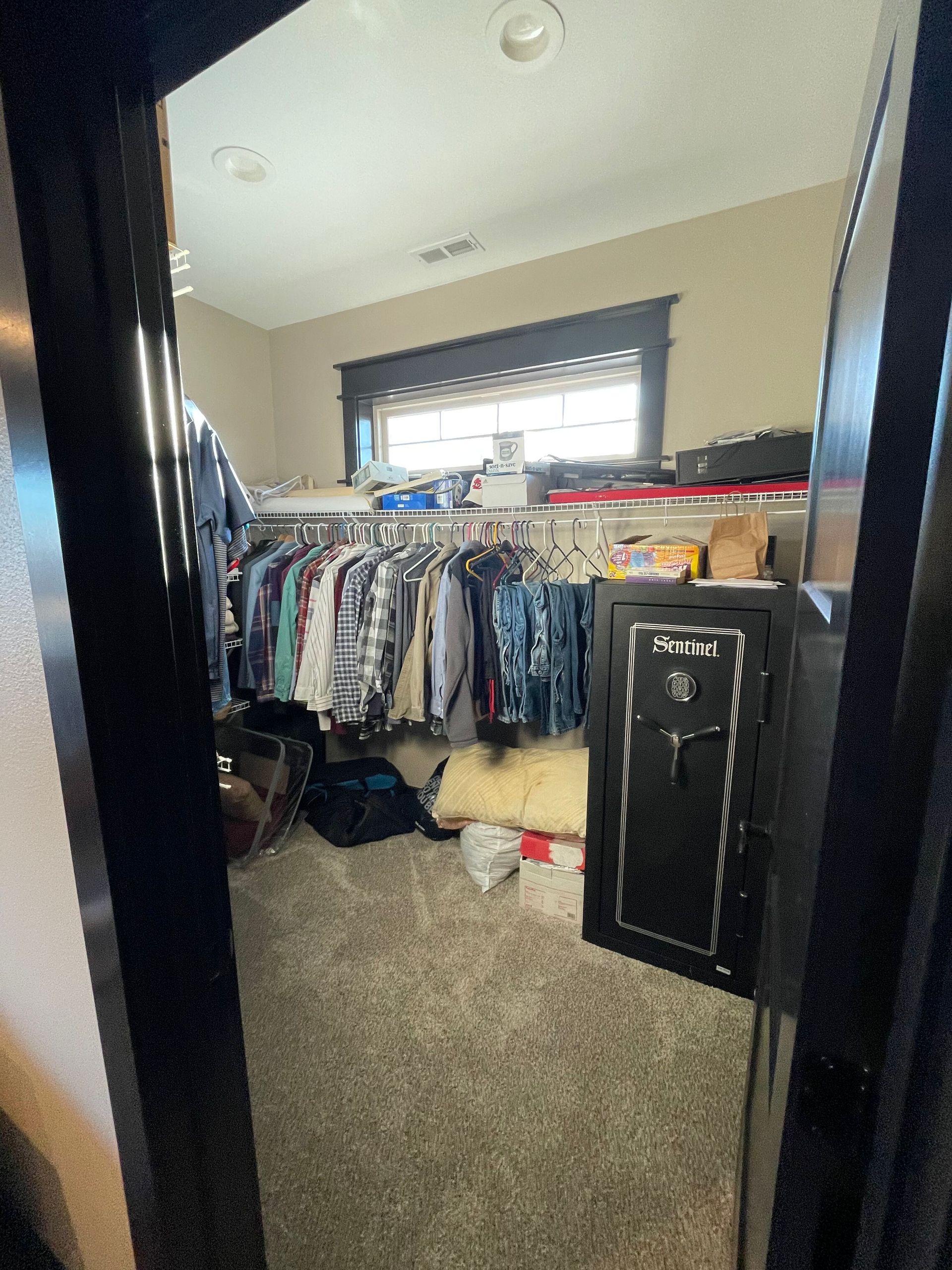 A walk in closet with clothes hanging on racks and a safe.