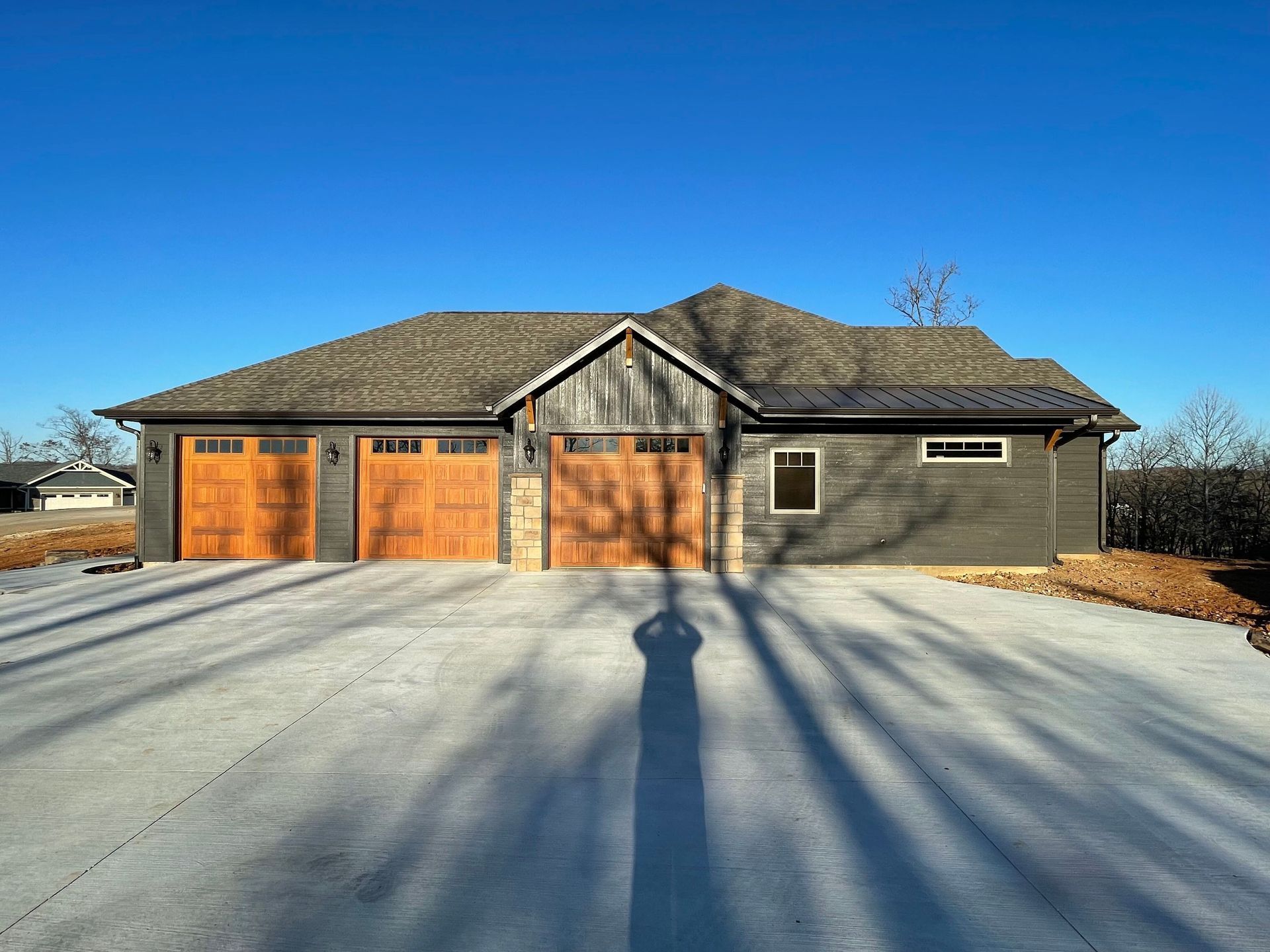 A large house with three garage doors is sitting on top of a concrete driveway.