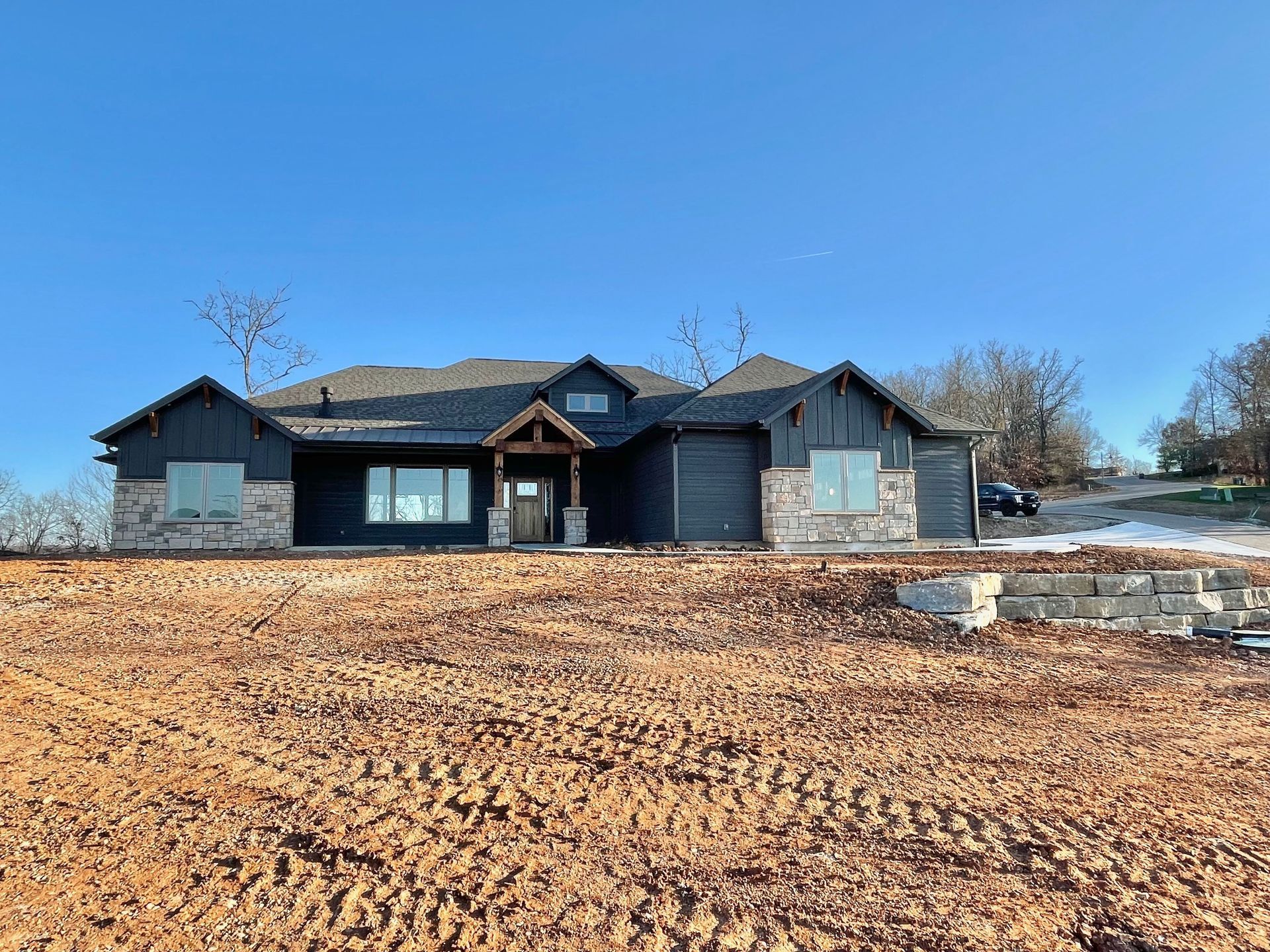 A large house is sitting in the middle of a dirt field.