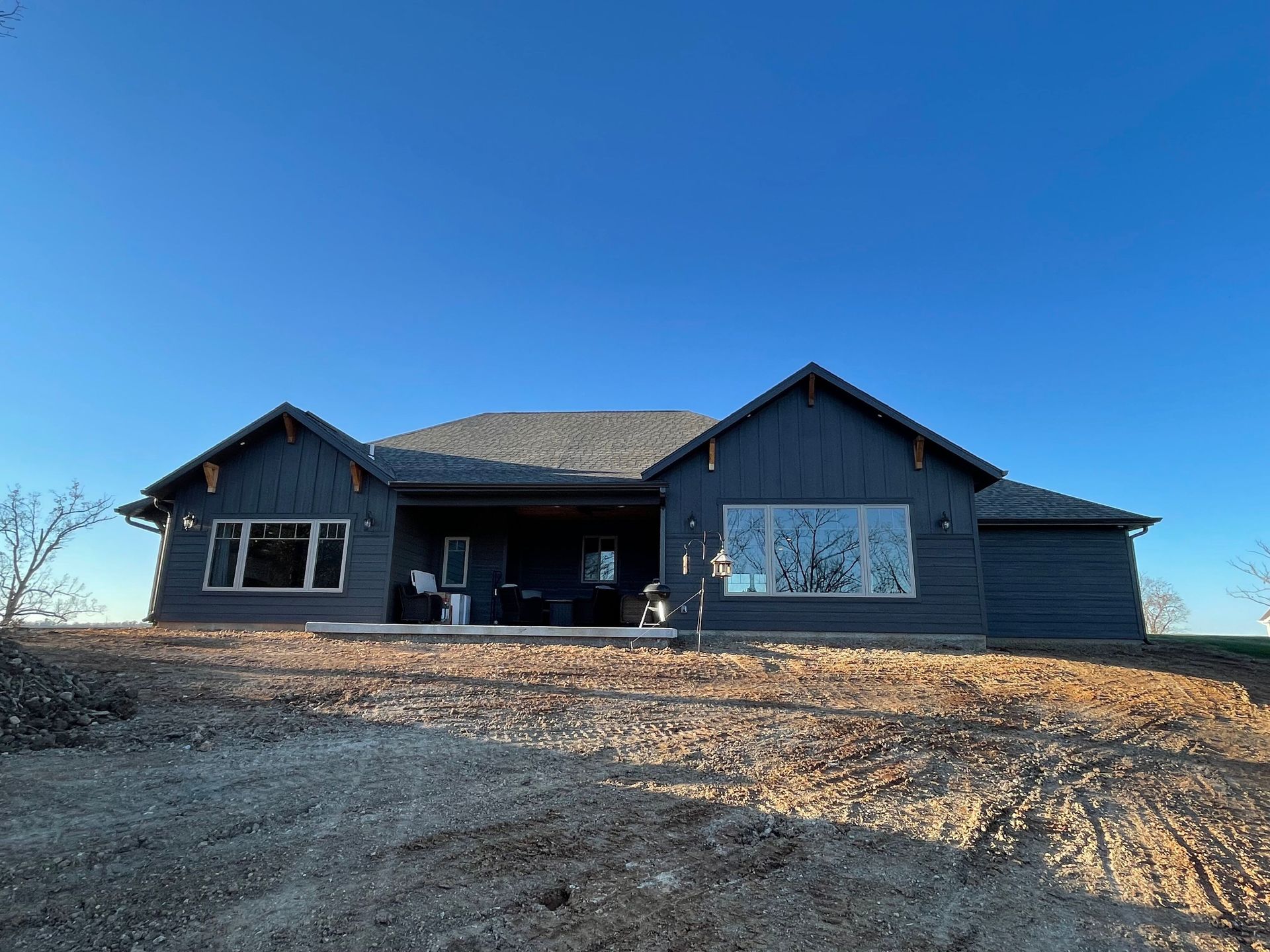 A large black house is sitting on top of a dirt hill.