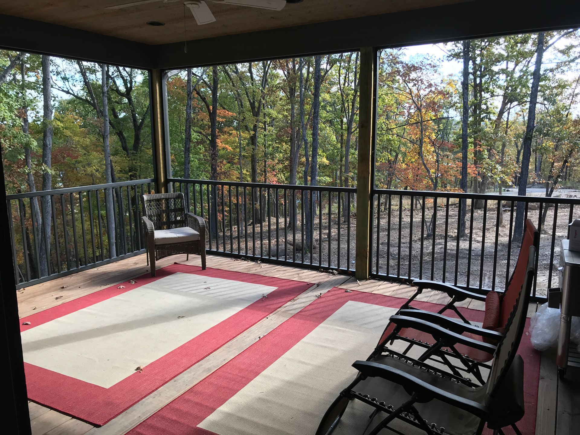 A screened in porch with rocking chairs and a rug.