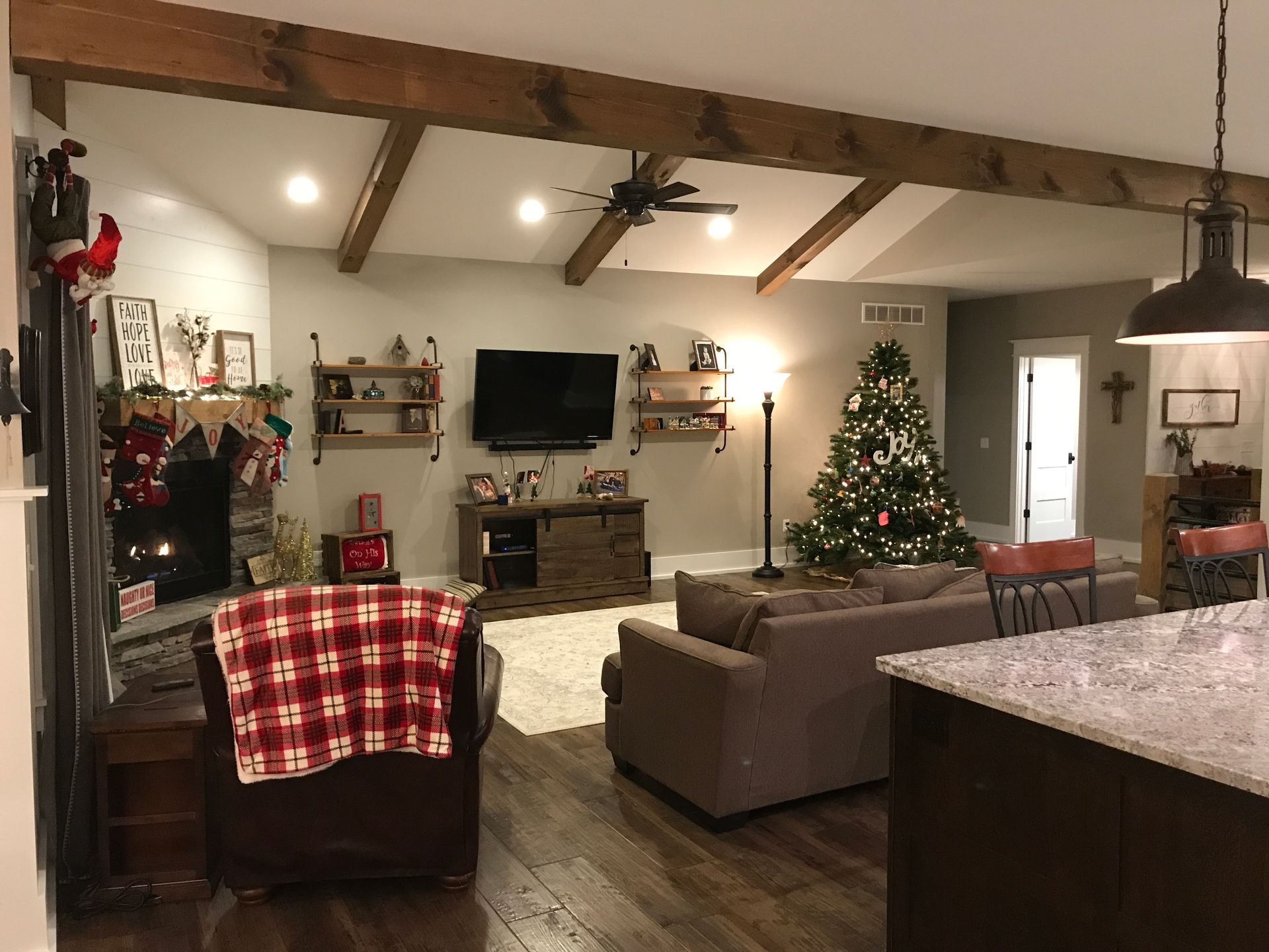 A living room with a couch , chair , television and a christmas tree.