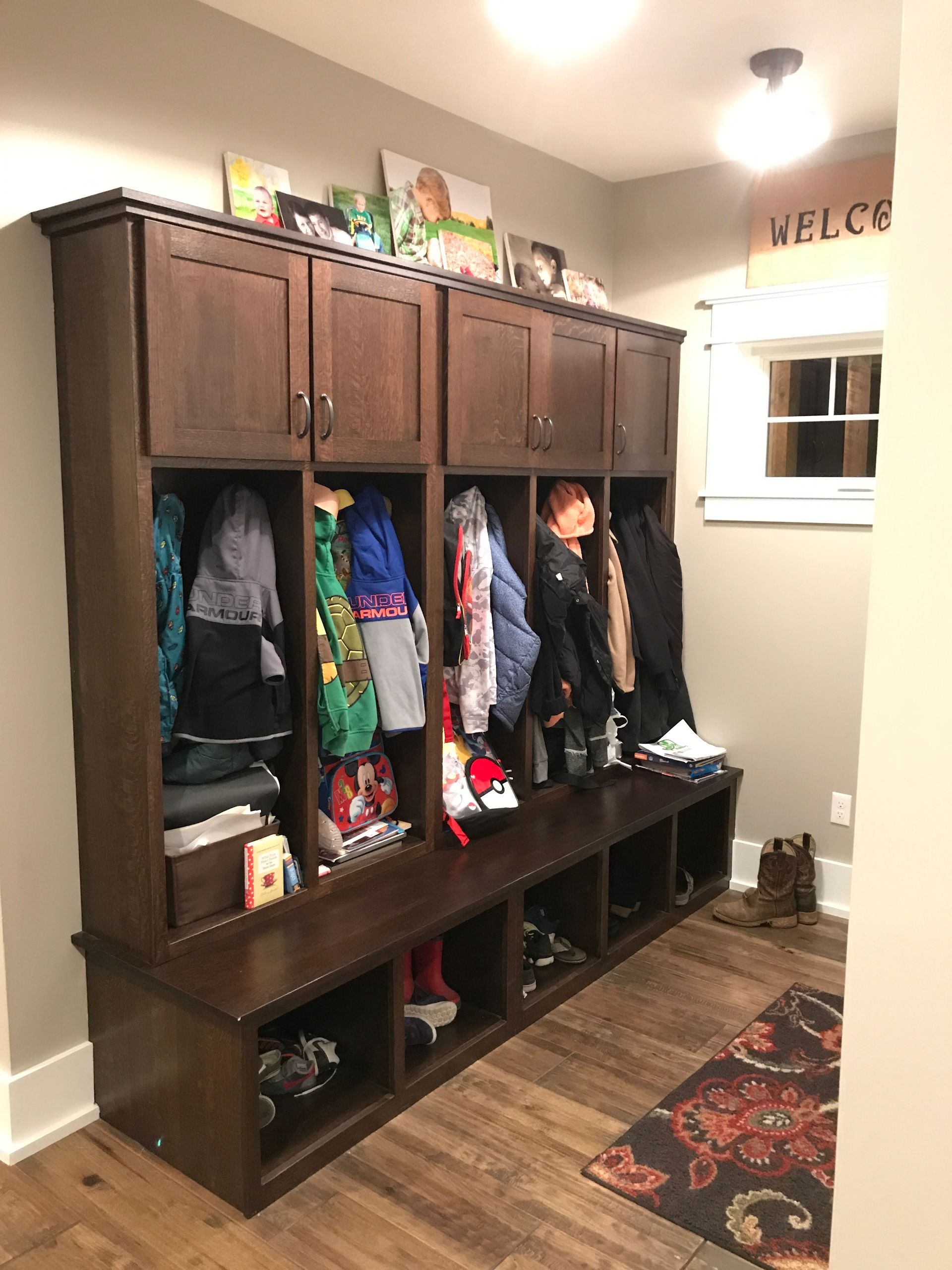 A mud room with a bench and cabinets filled with clothes and shoes.
