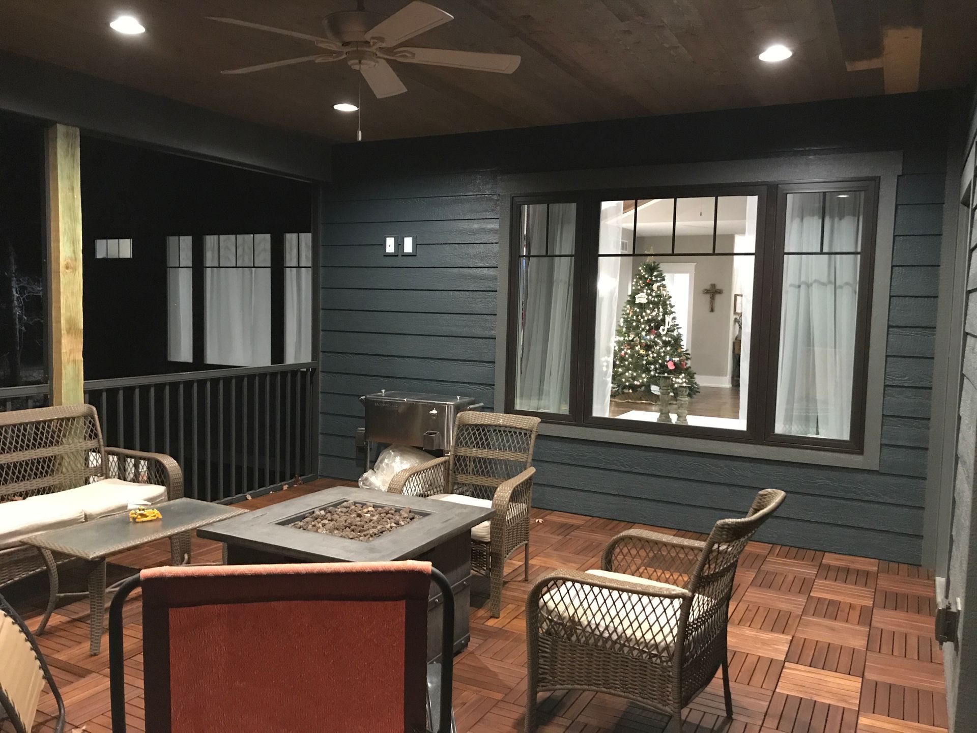 A porch with a fire pit and a christmas tree in the window