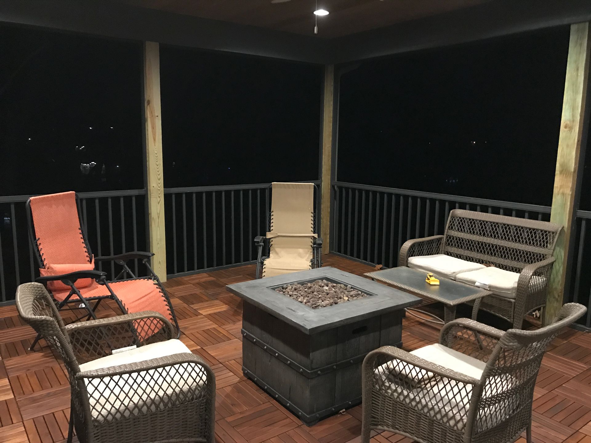 A porch with furniture and a fire pit at night.