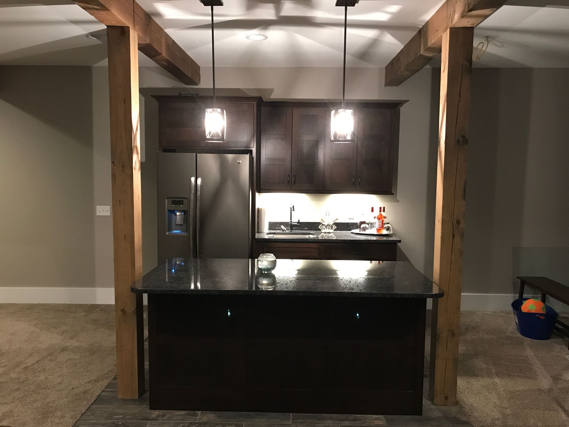 A kitchen with a large island and a stainless steel refrigerator